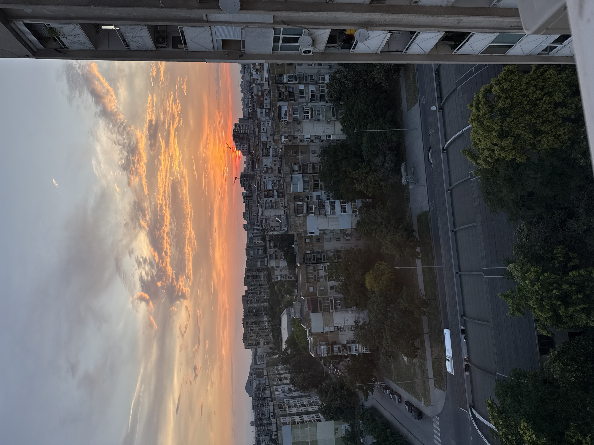 Sunset over the city while a soccer match plays indoors