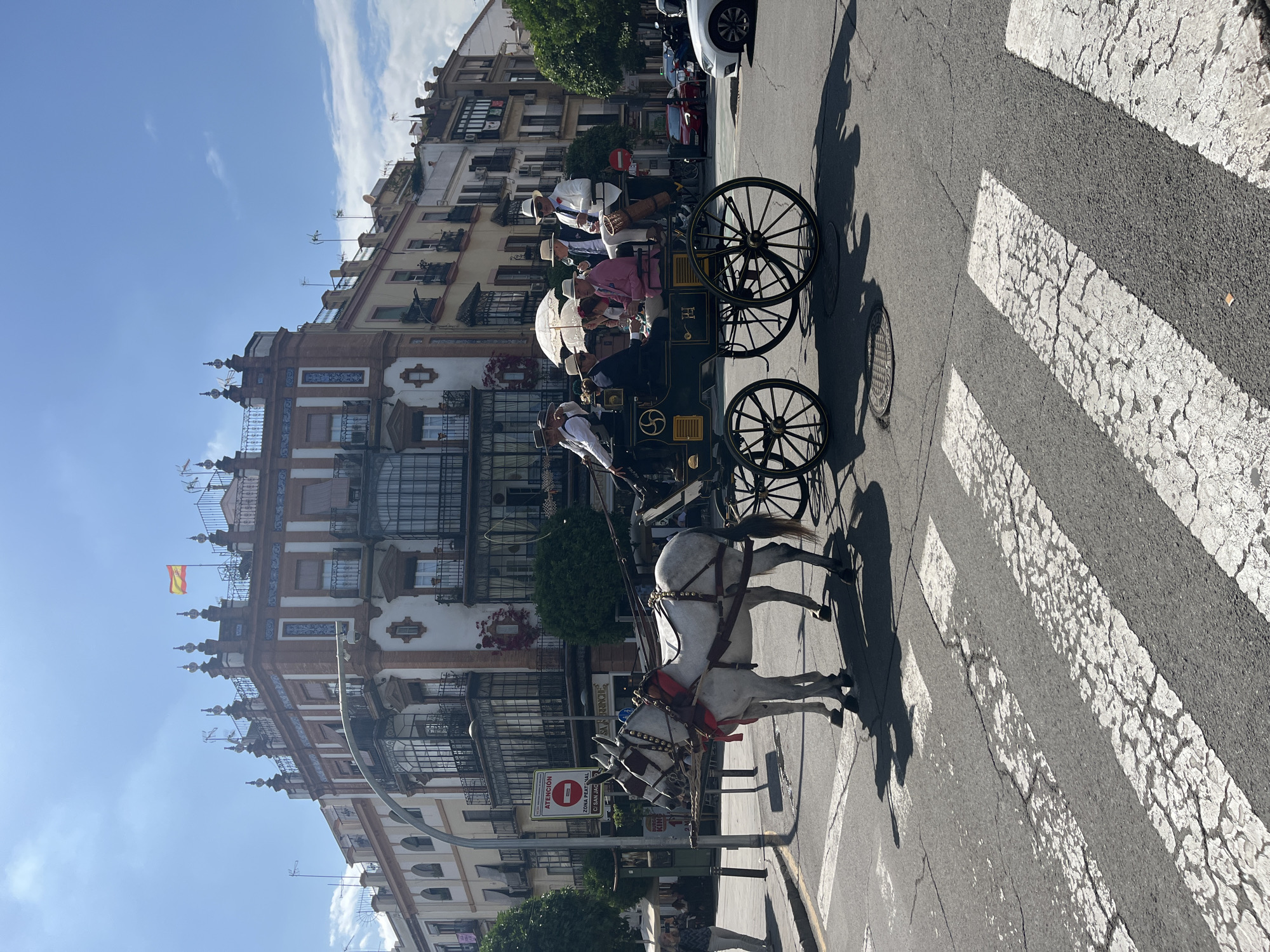 Horse carriage crosses pedestrian walkway in busy Seville square