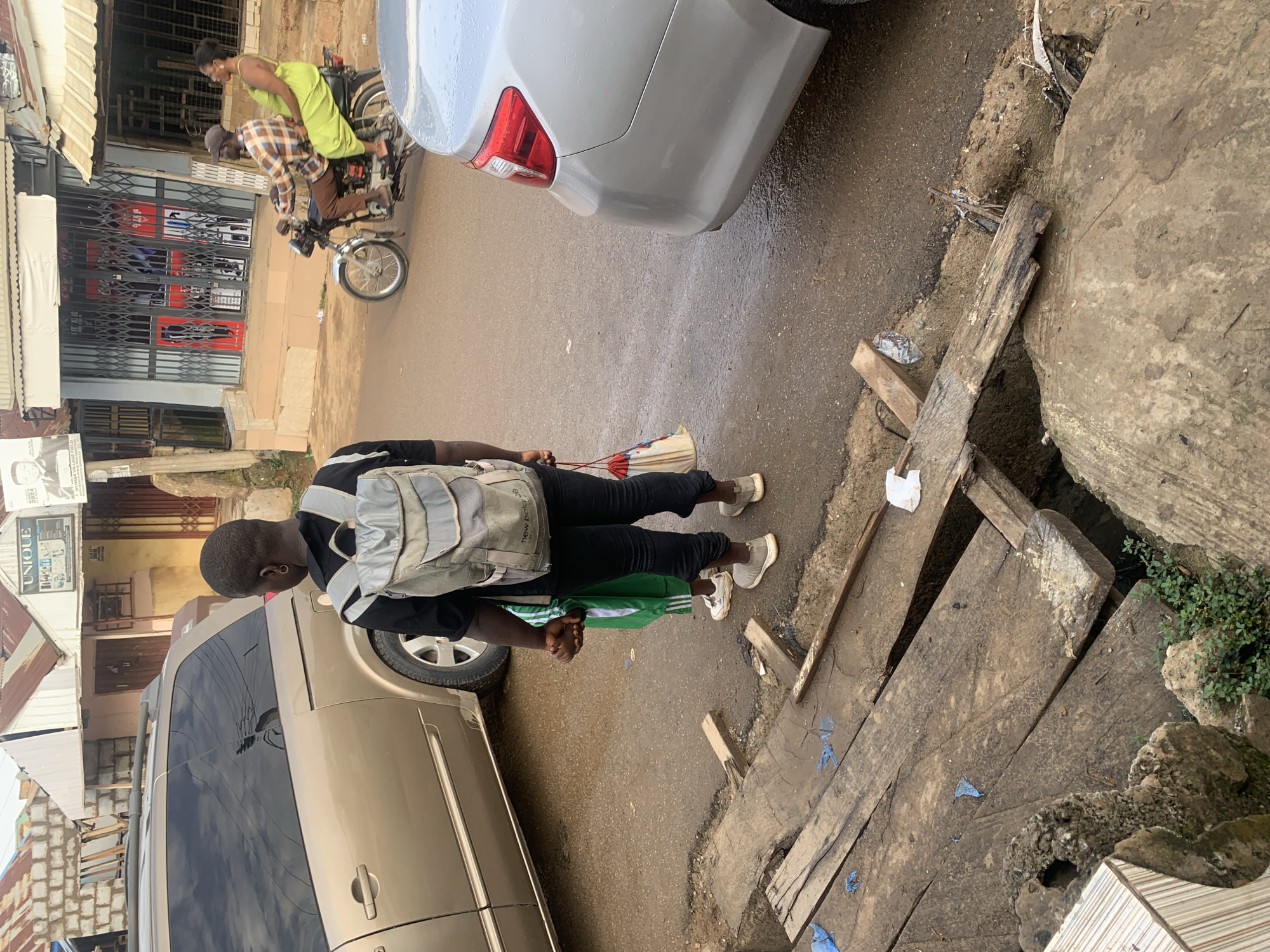 Morning street life in Abuja after rainfall, kids and commuters out