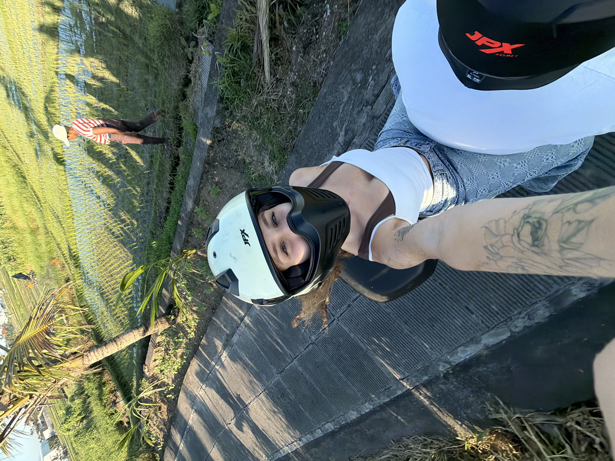 Woman takes motorcycle selfies near rice field in North Kuta