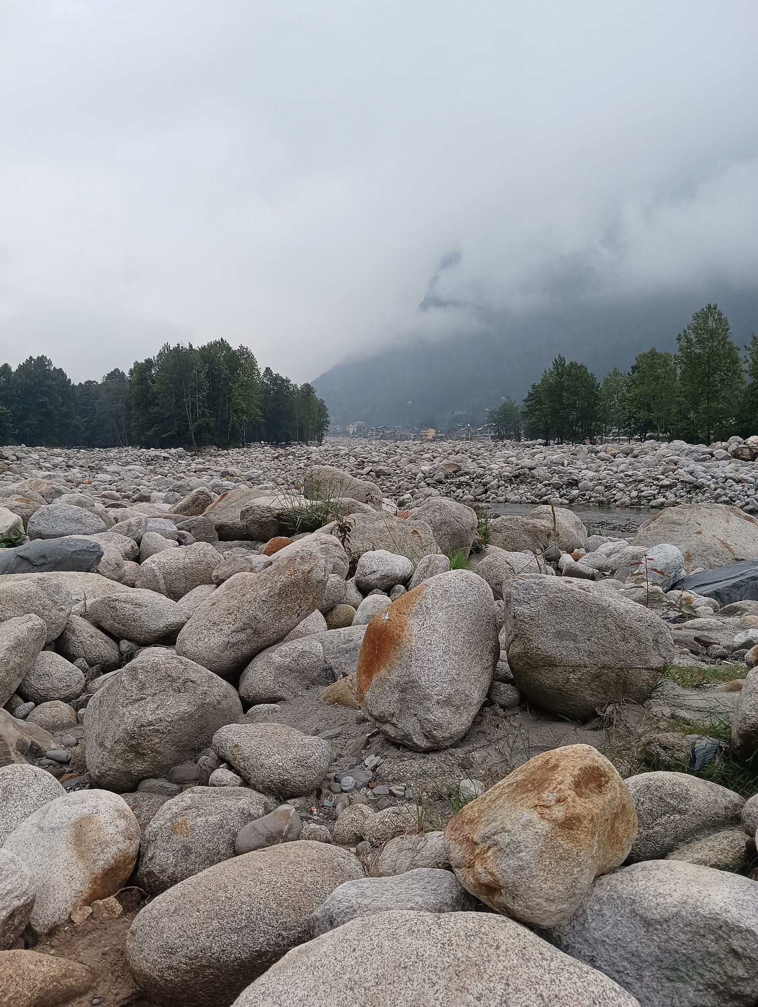 Rocky riverbed, forest road, and camp tents in Goshal, India
