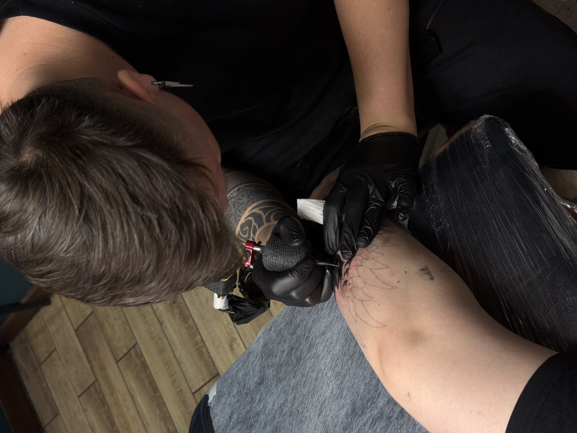 Tattoo artist works on client's arm design in Orenburg studio