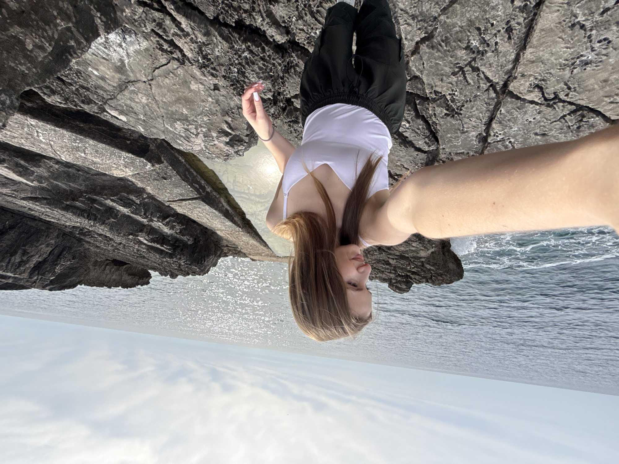 Woman stands on rocky Budva coastline overlooking Adriatic Sea