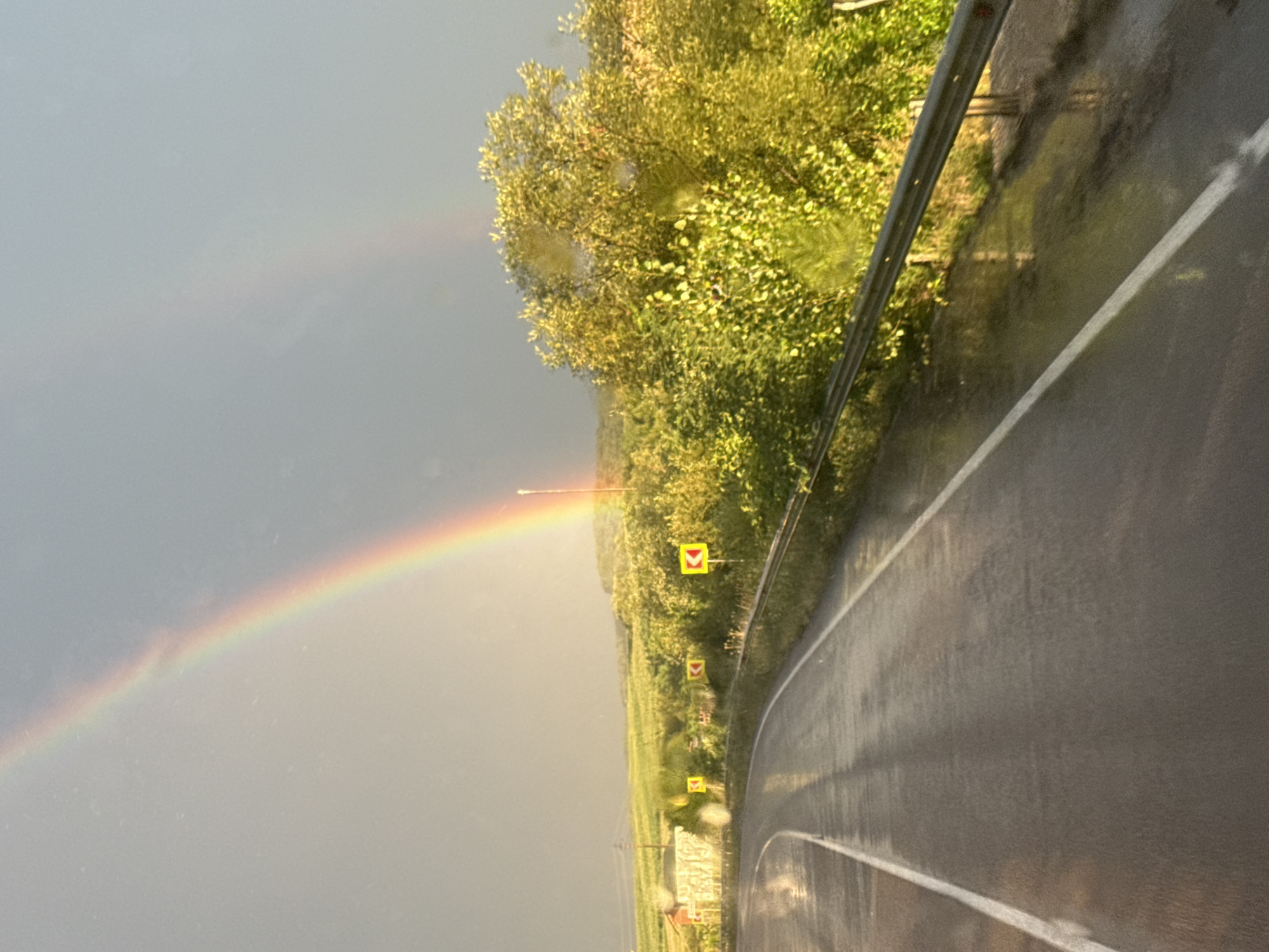 Double rainbow over a wet rural road after rain