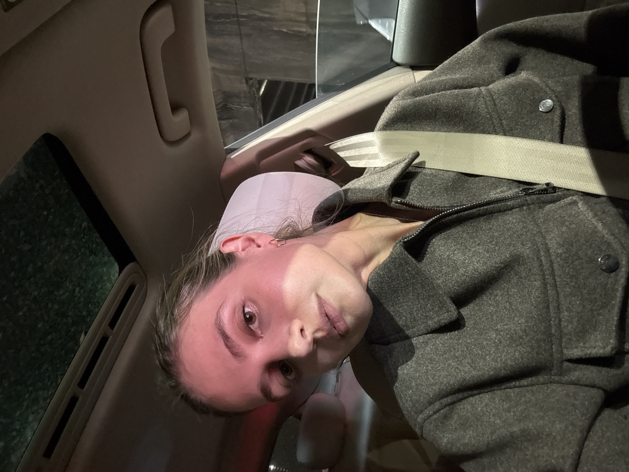 Woman in gray coat photographed during morning car ride