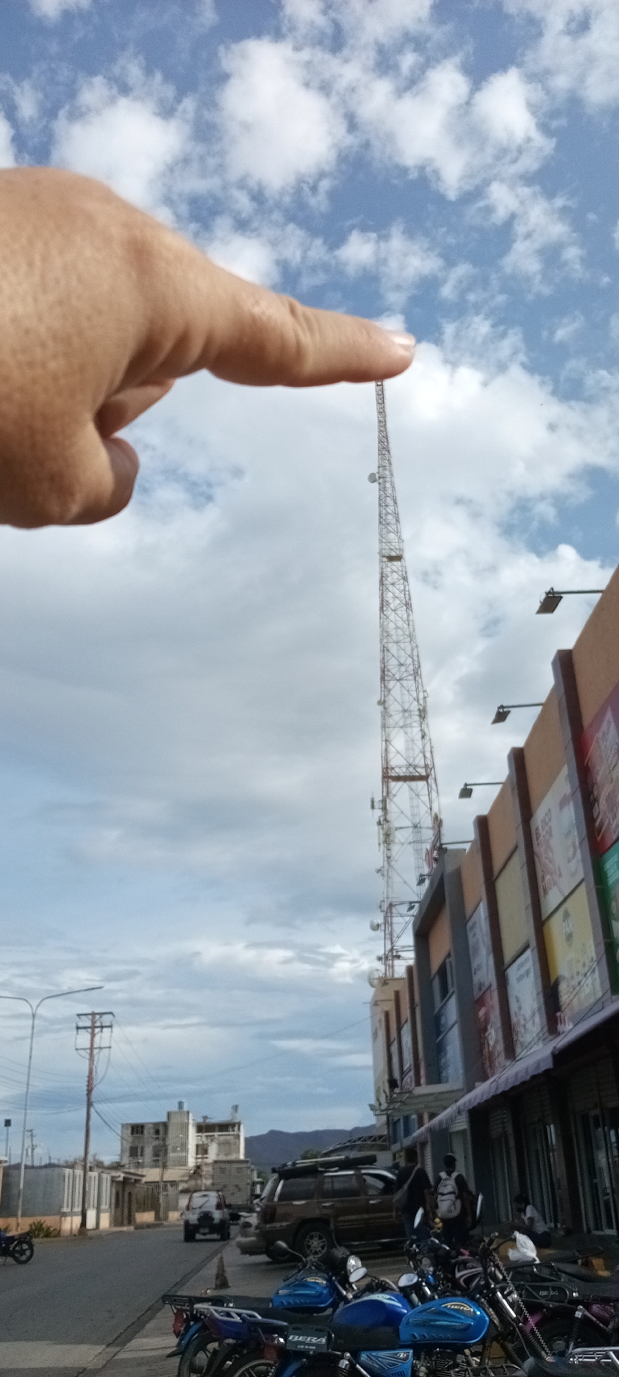 Person gestures at telecommunications tower while pedestrian passes