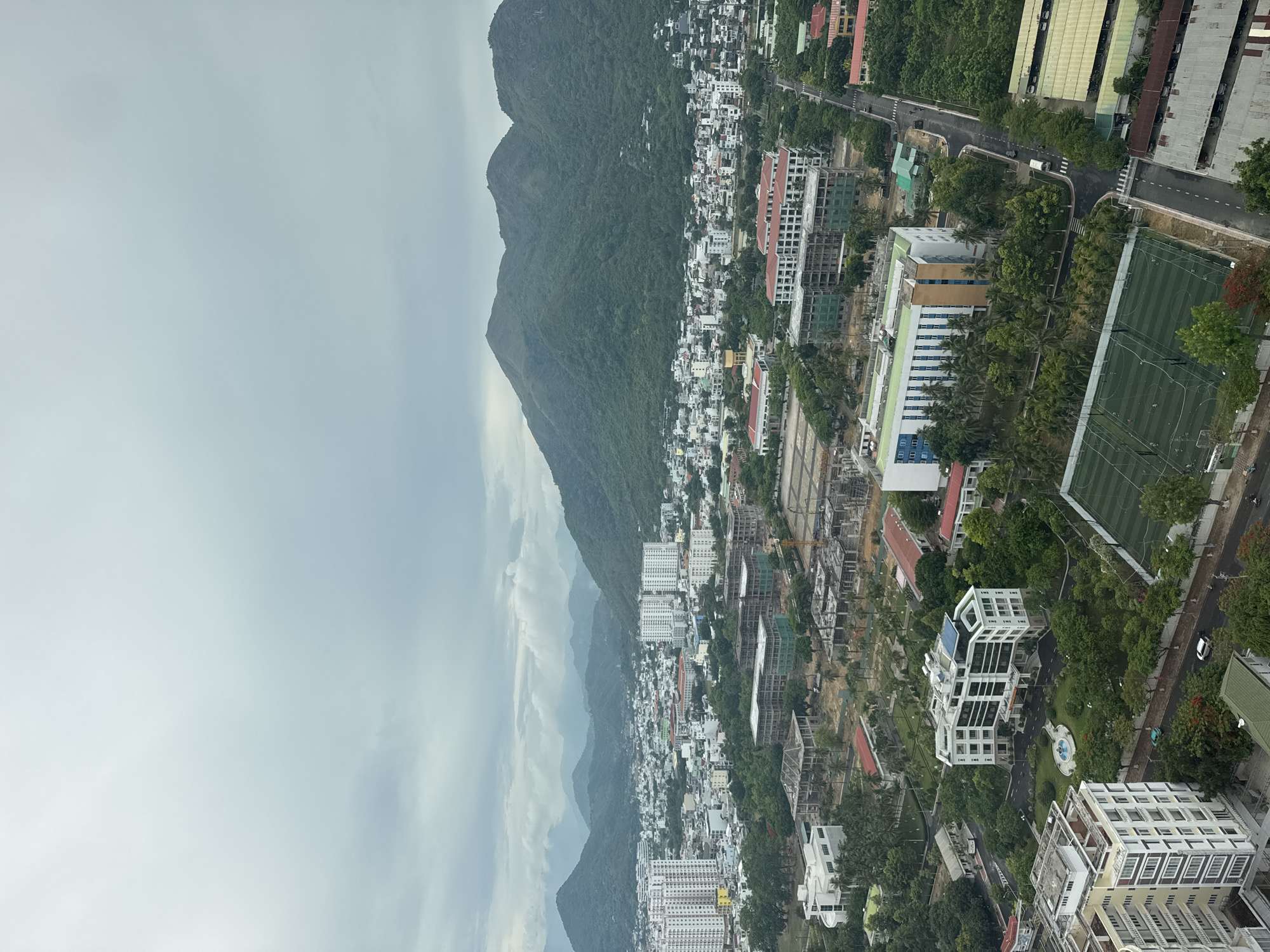 Aerial views of a tropical coastal city against green mountains