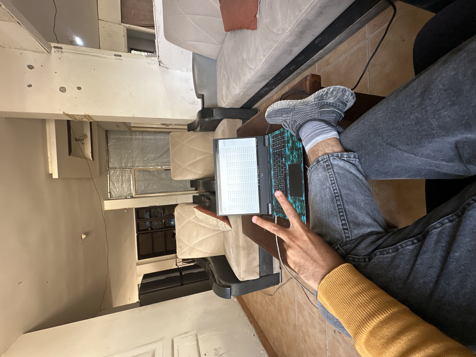 Person works on laptop, man rests on sofa in Gaza