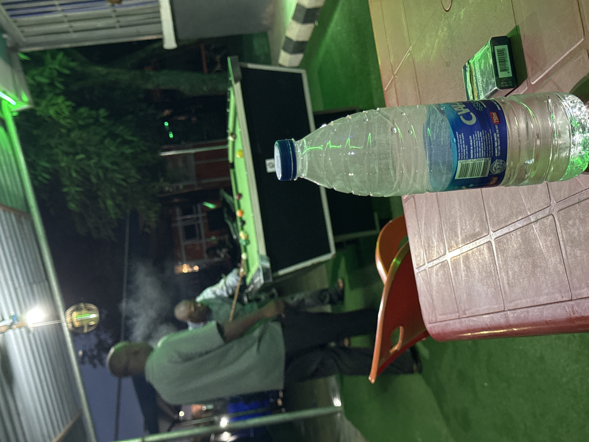 Men play nighttime billiards outdoors in Karu, Nigeria