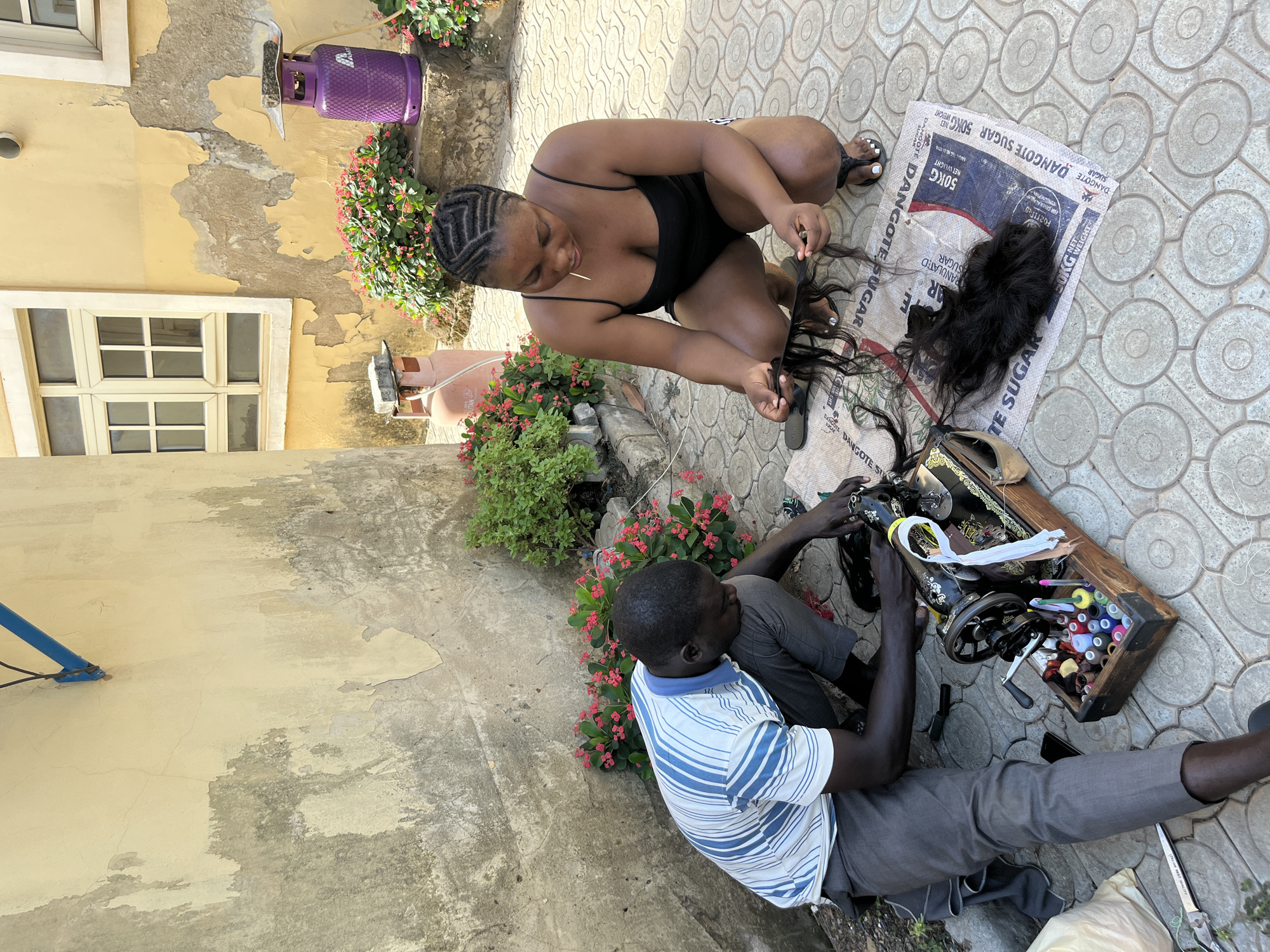 Outdoor sewing and textile work documented in Abuja neighborhood