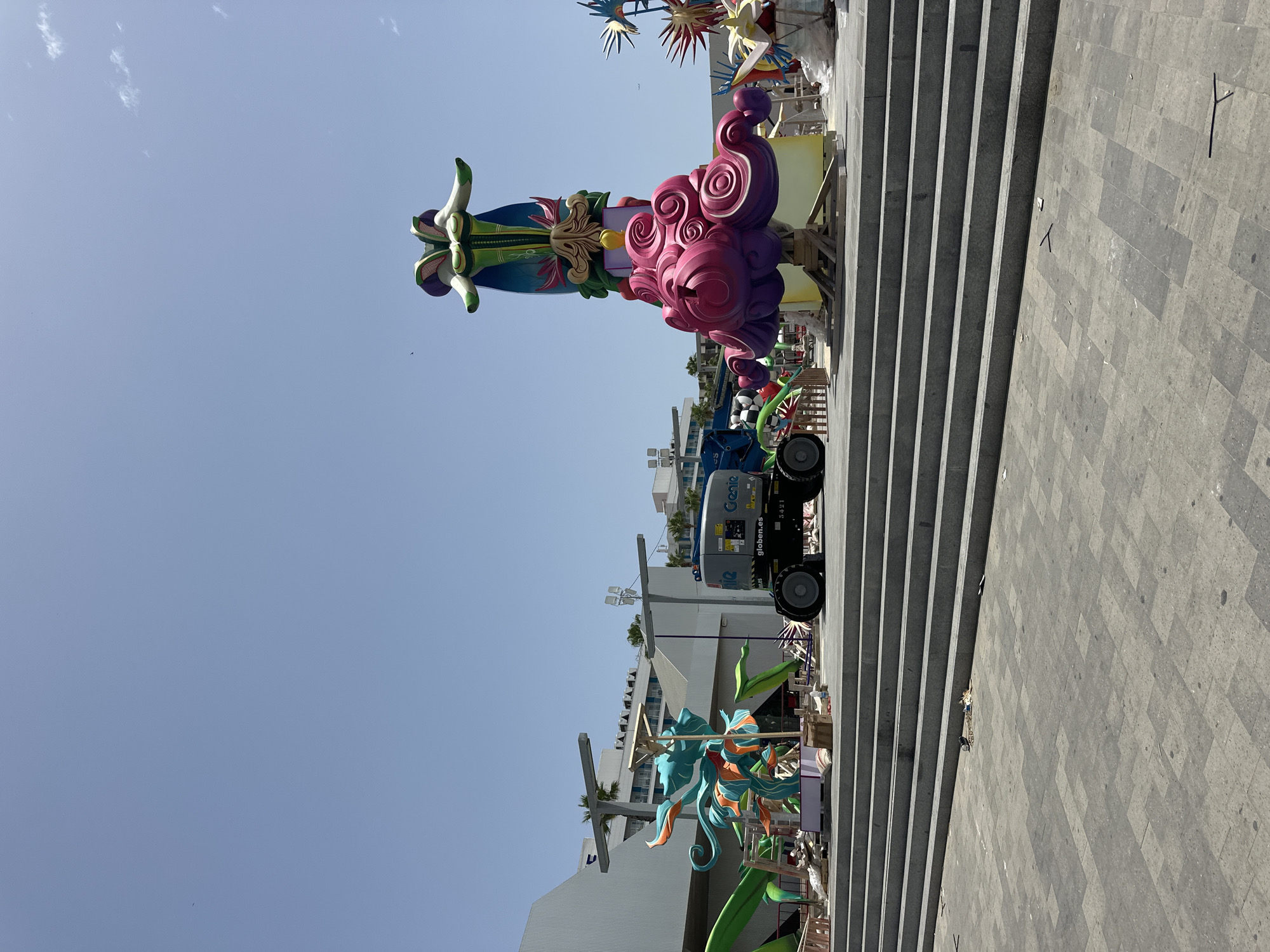 Busy Mediterranean promenade with beach crowds, palms, and street art