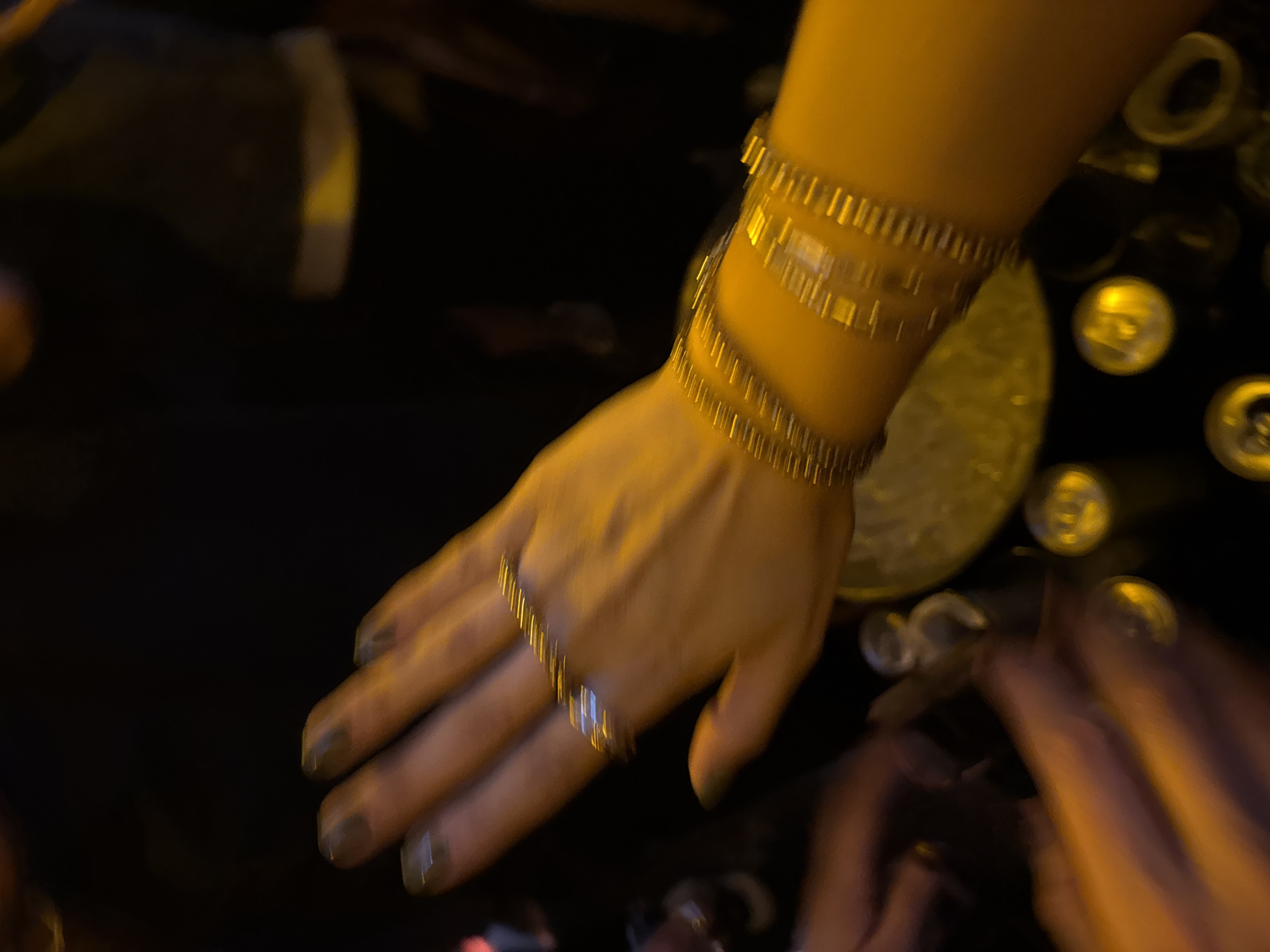Person with gold jewelry reaches toward table in Mexico City