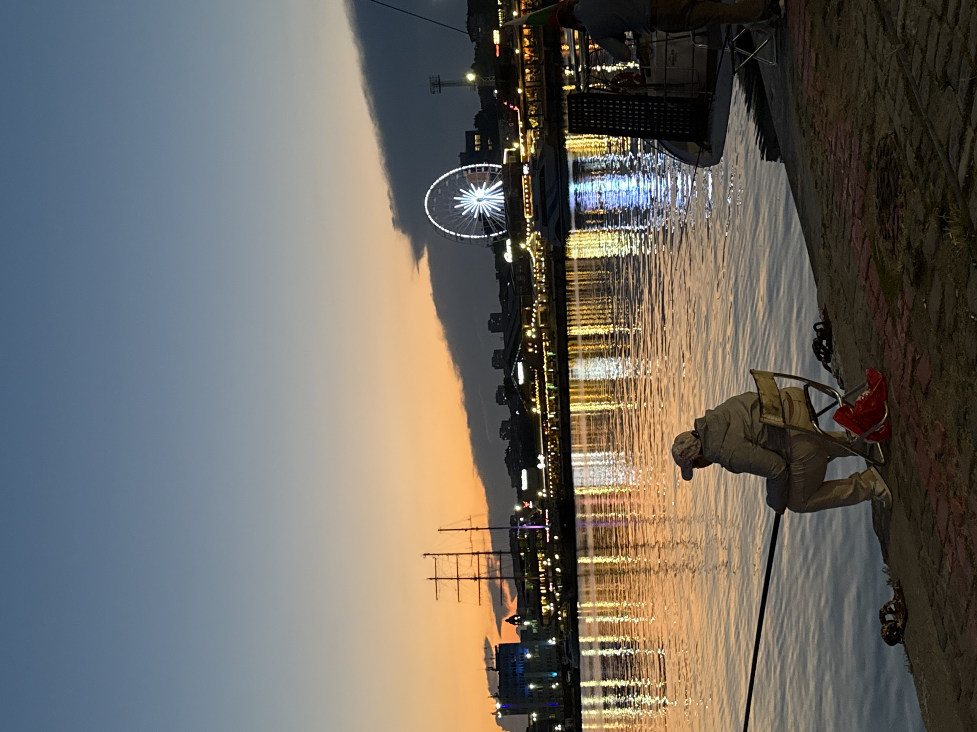 Evening fishing and social gathering observed at waterfront promenade