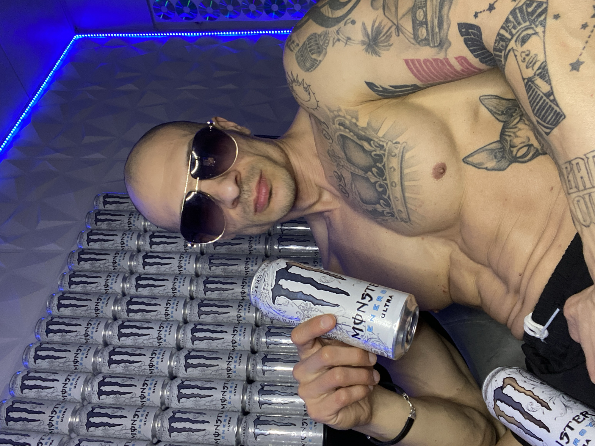 Man poses with Monster Energy cans in LED-lit room