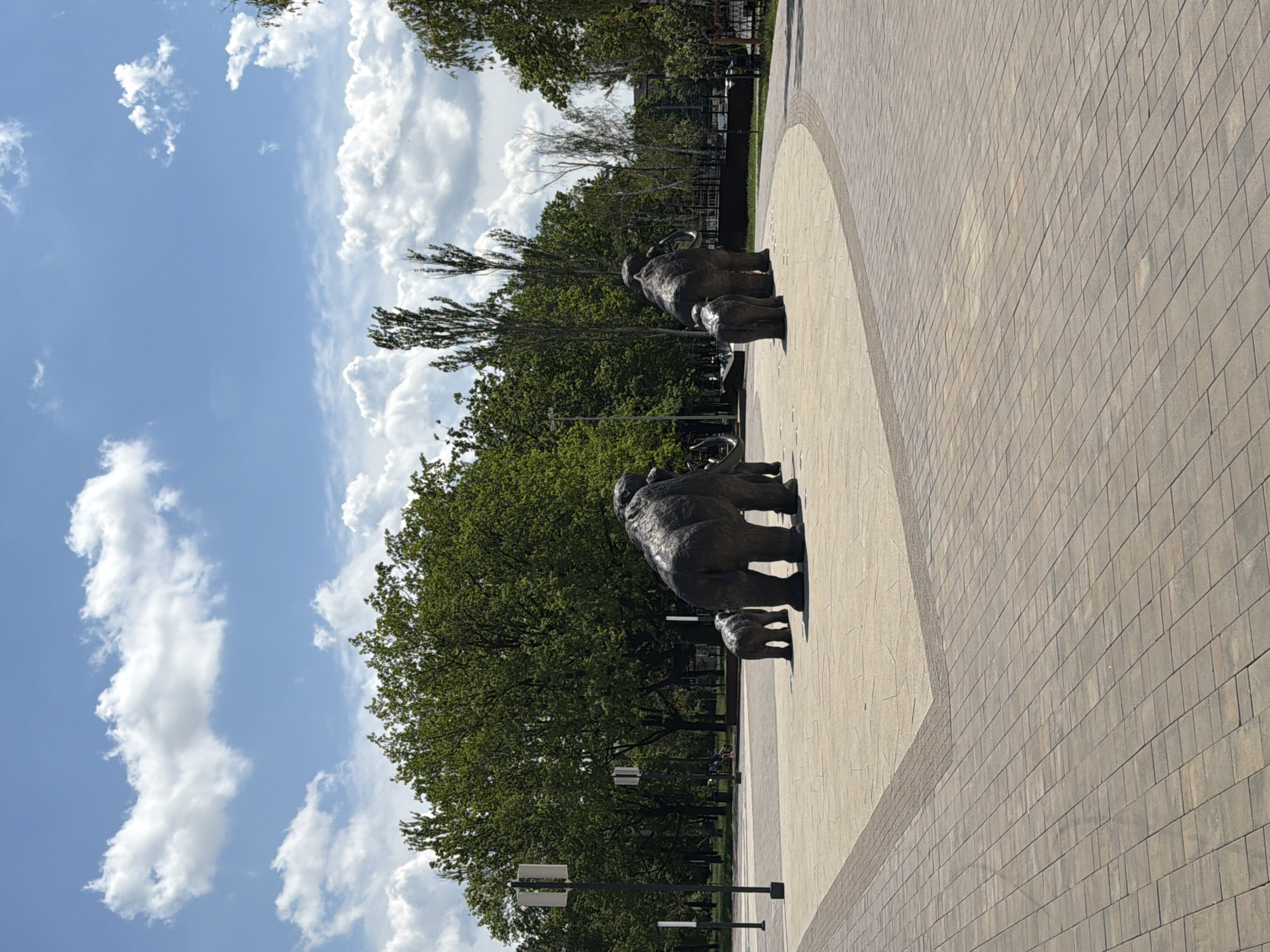 Kid explores a sunny urban park with elephant sculptures