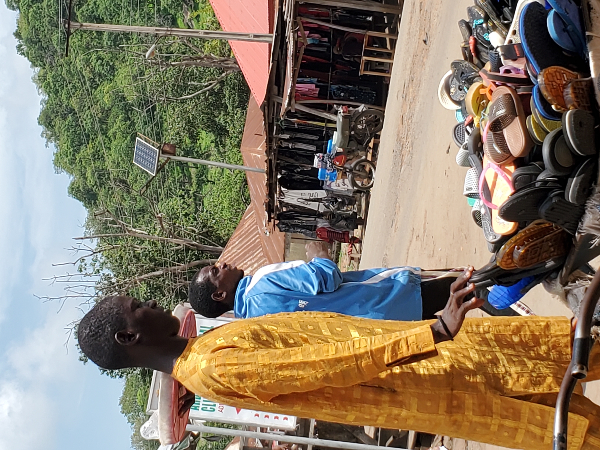Two men browse sandals at street vendor in Mararaba