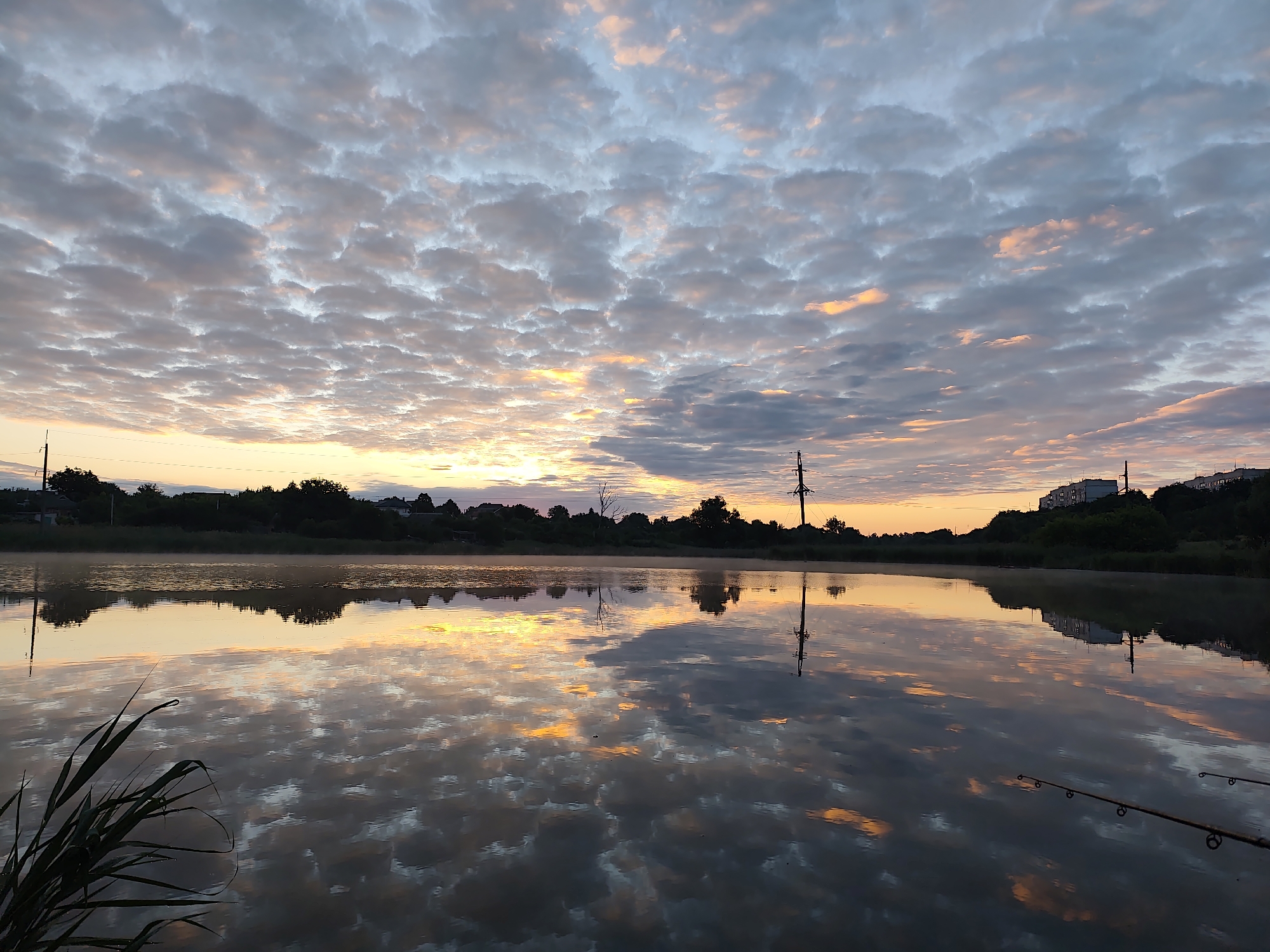 Sunrise clouds reflecting over a still lake in Khroly, Ukraine