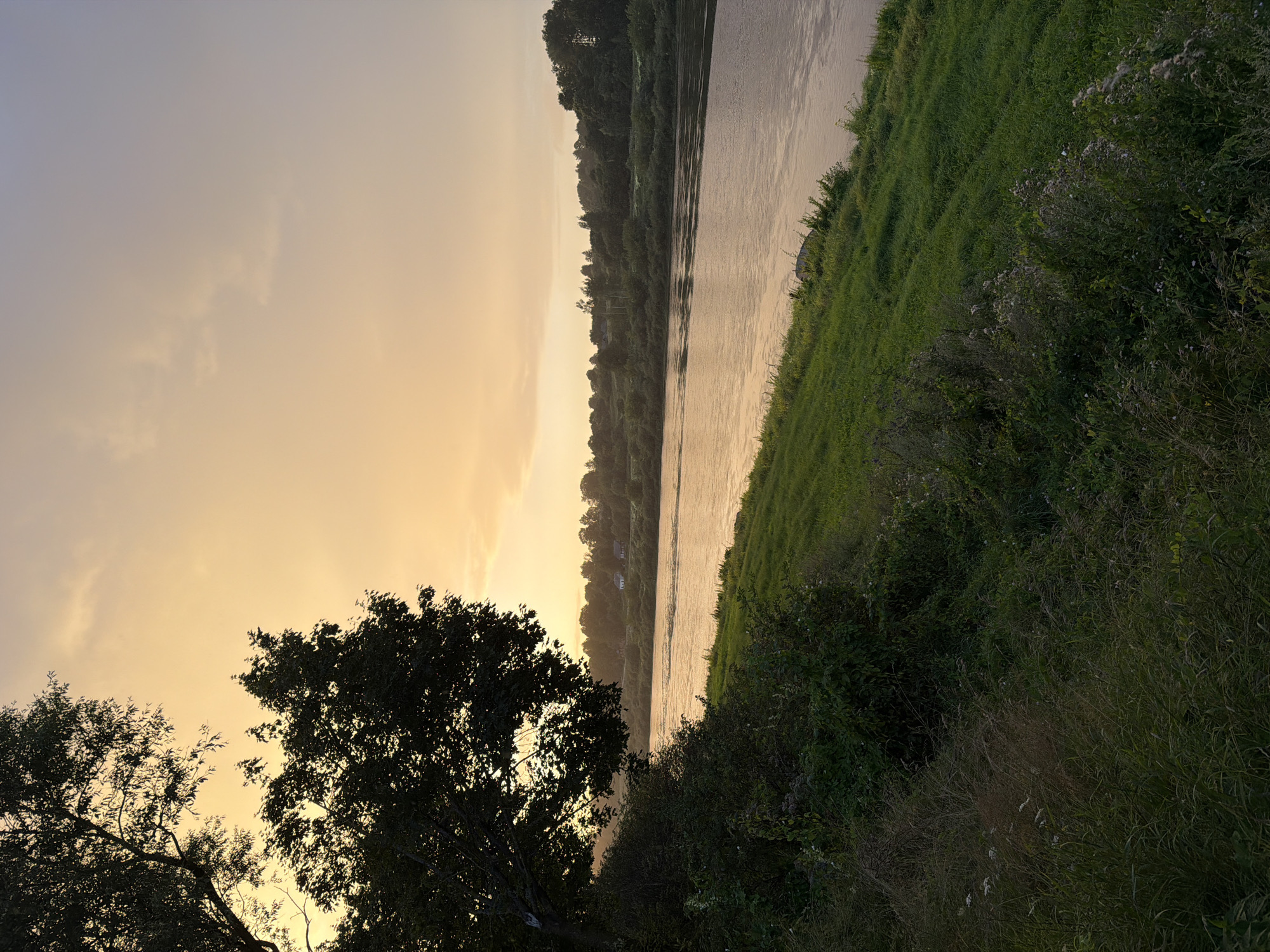 Orthodox church, river, and rainbow at rural sunset
