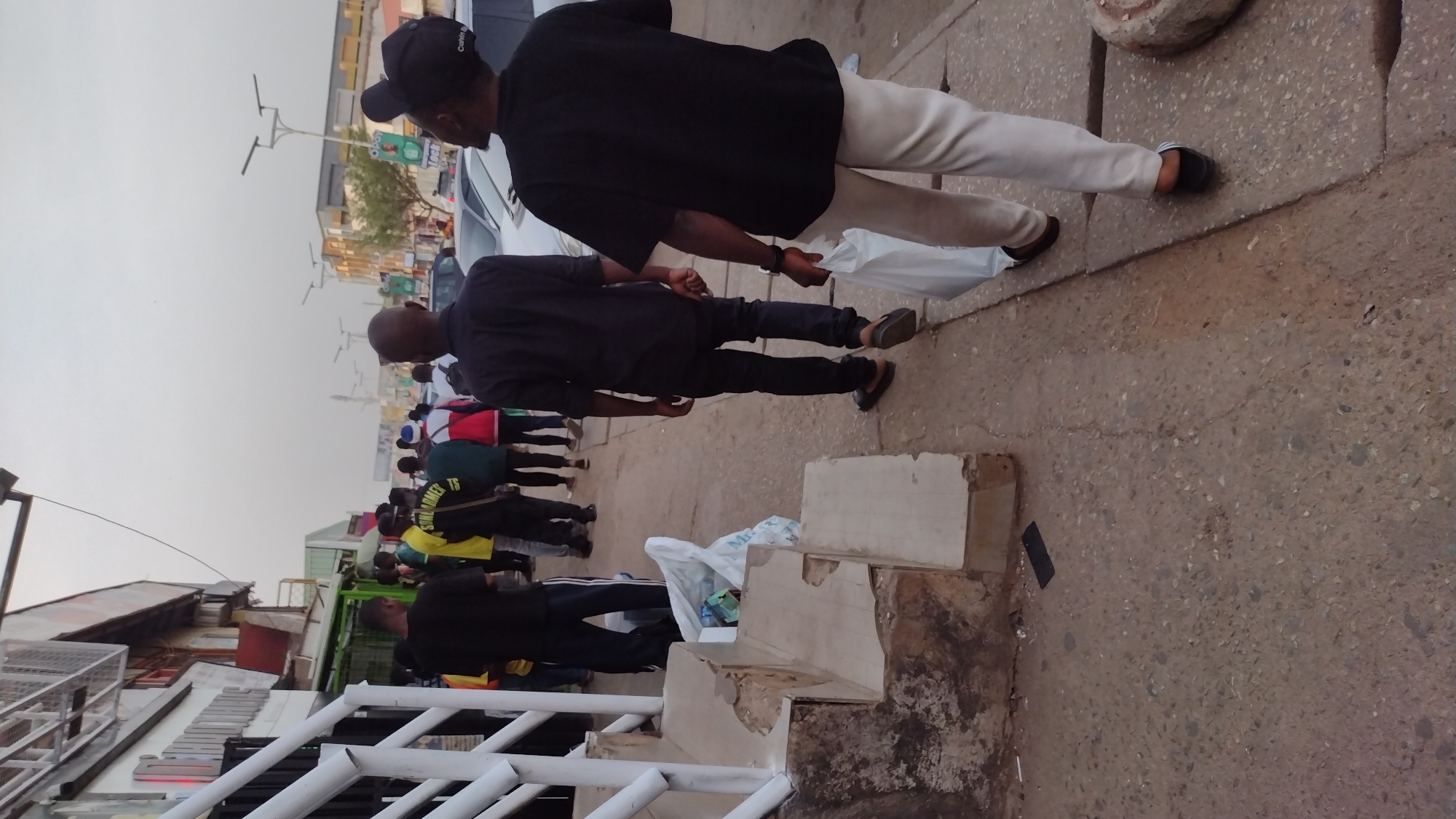 Two men in black shirts walk Jos sidewalk