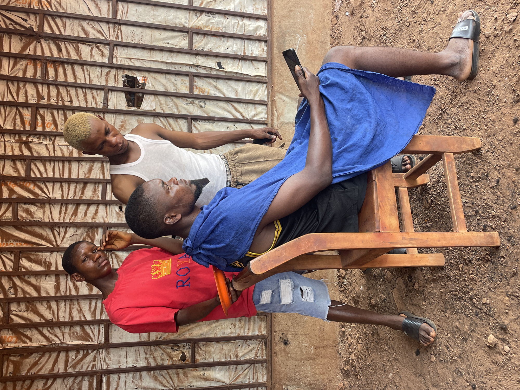 Three young men gather outdoors in Ogbe, Nigeria