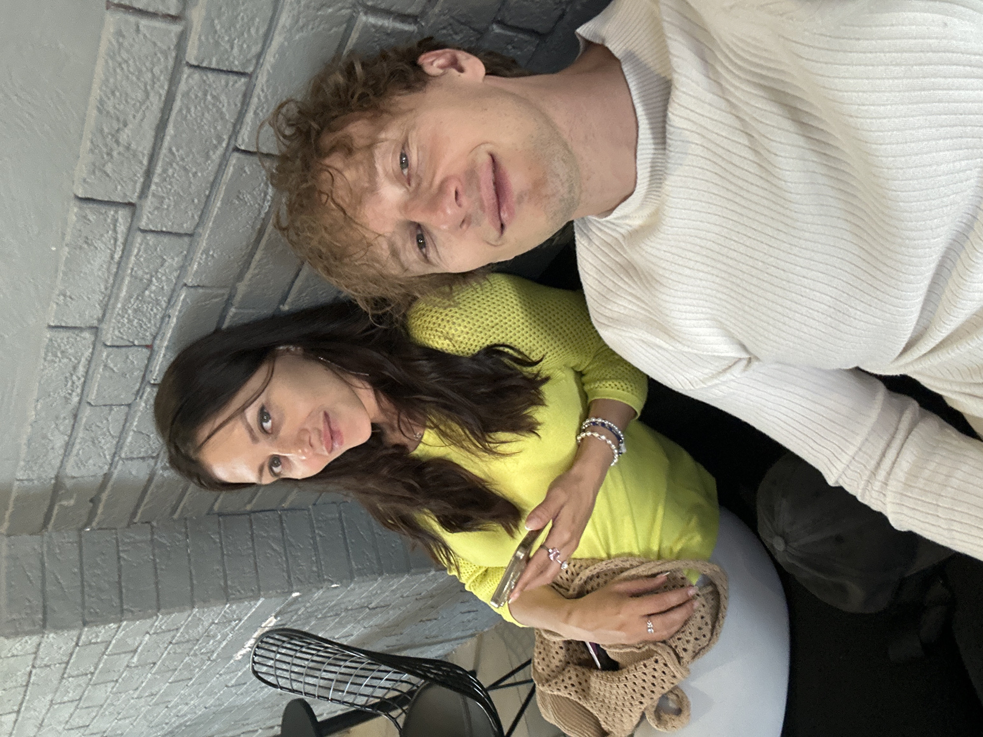 Two people pose against a brick wall in Murino