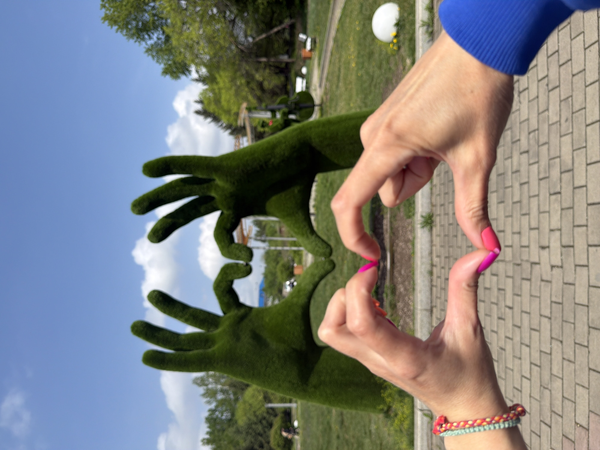 Woman photographs topiary hand sculptures in Birobidzhan park