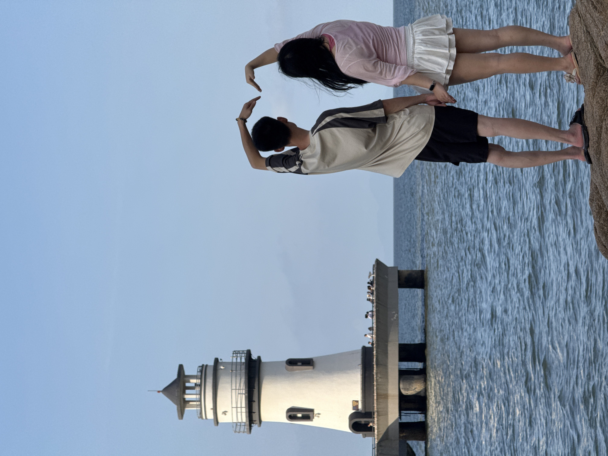 Tourists pose at scenic Xiangzhou coastal lighthouse during morning visit