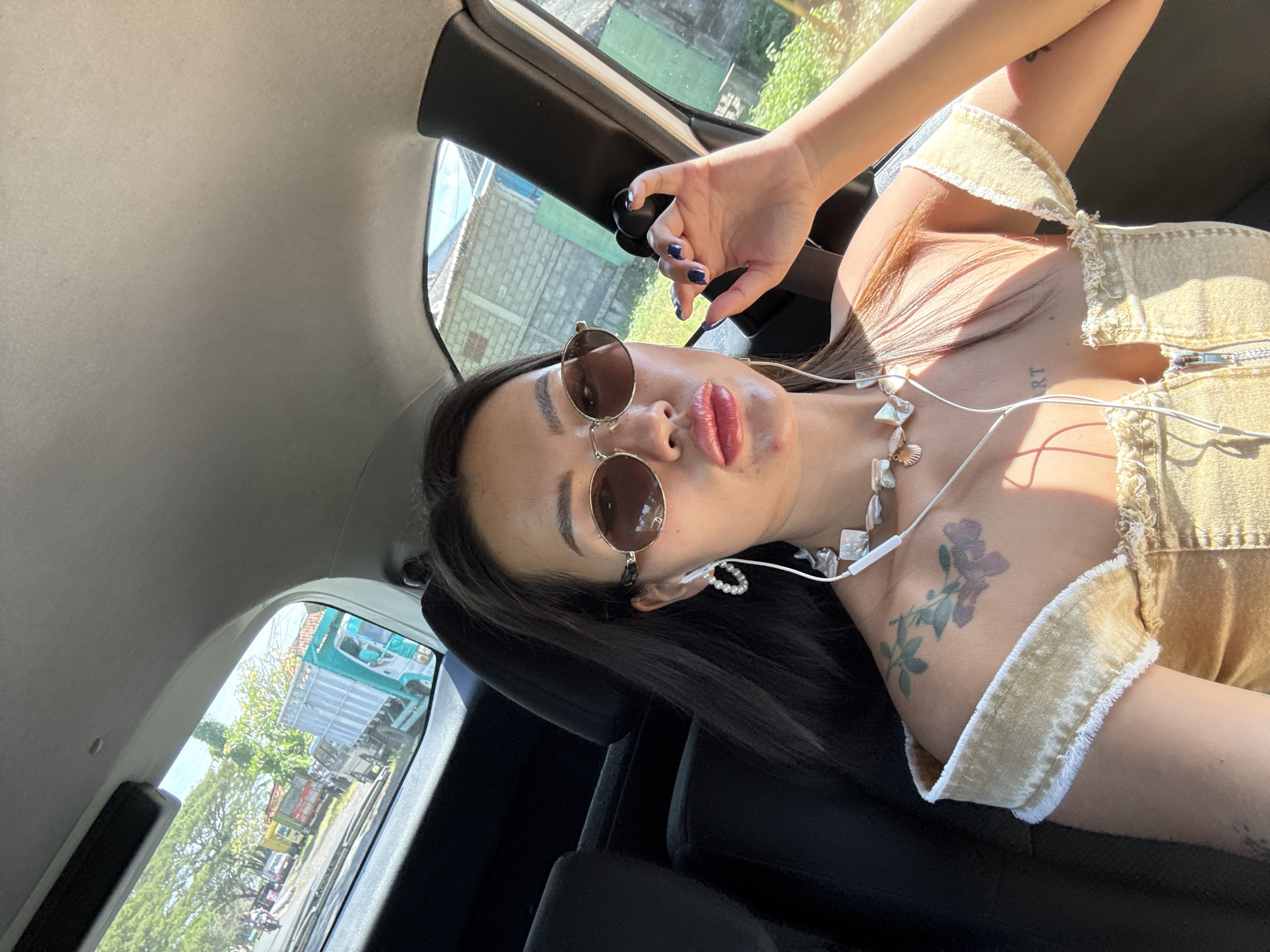 Woman photographed in passenger seat wearing gold accessories, Dawan