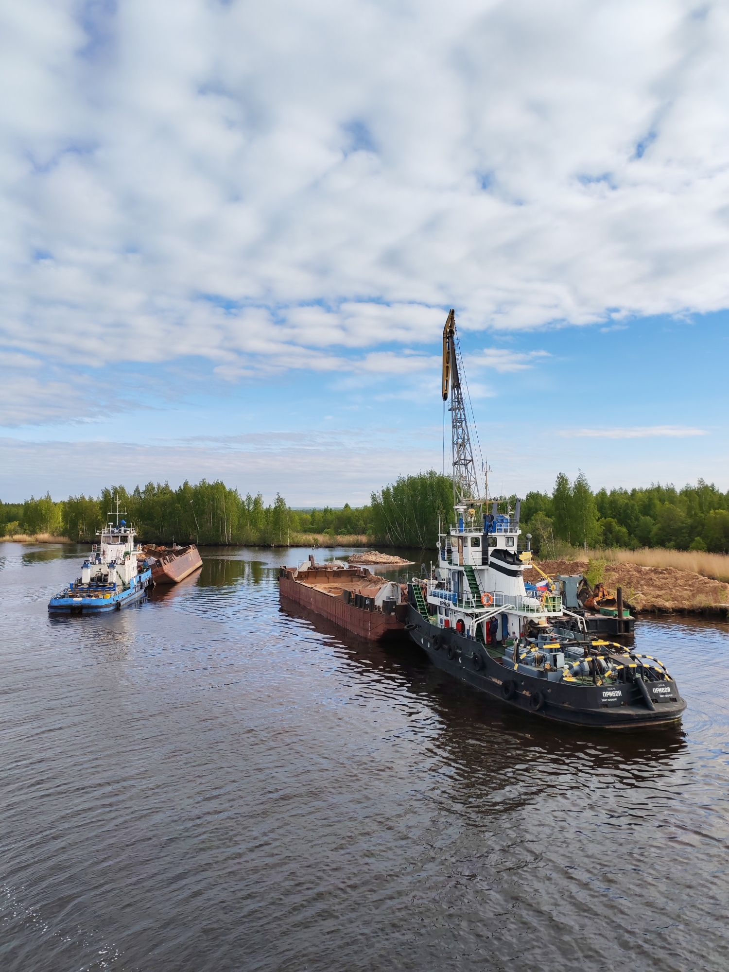 Tugboats and cargo barge conduct operations at Russian waterway