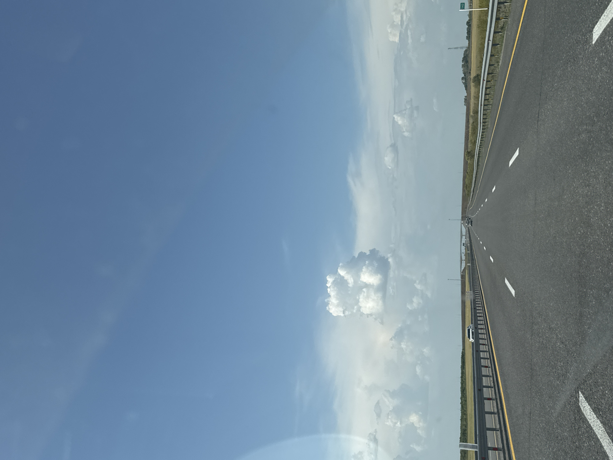 Open highway stretches into the Kazakh steppe under clear skies