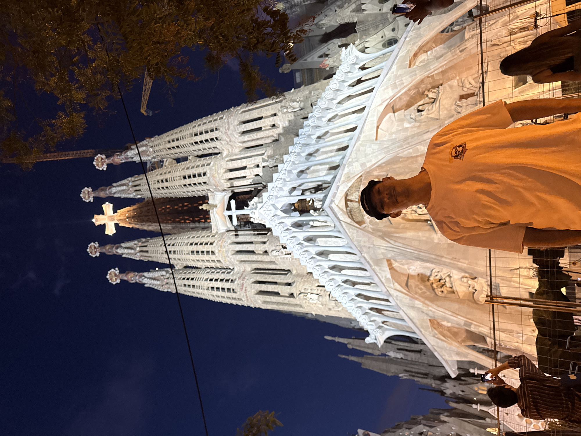 Evening tourists photograph illuminated Sagrada Familia in Barcelona