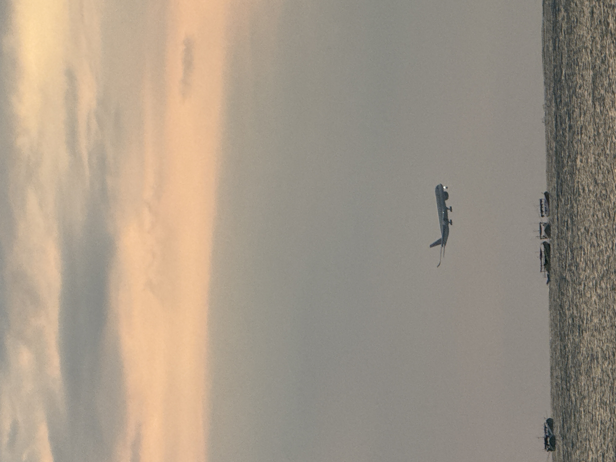 Plane on approach over Kuta's coast at sunset