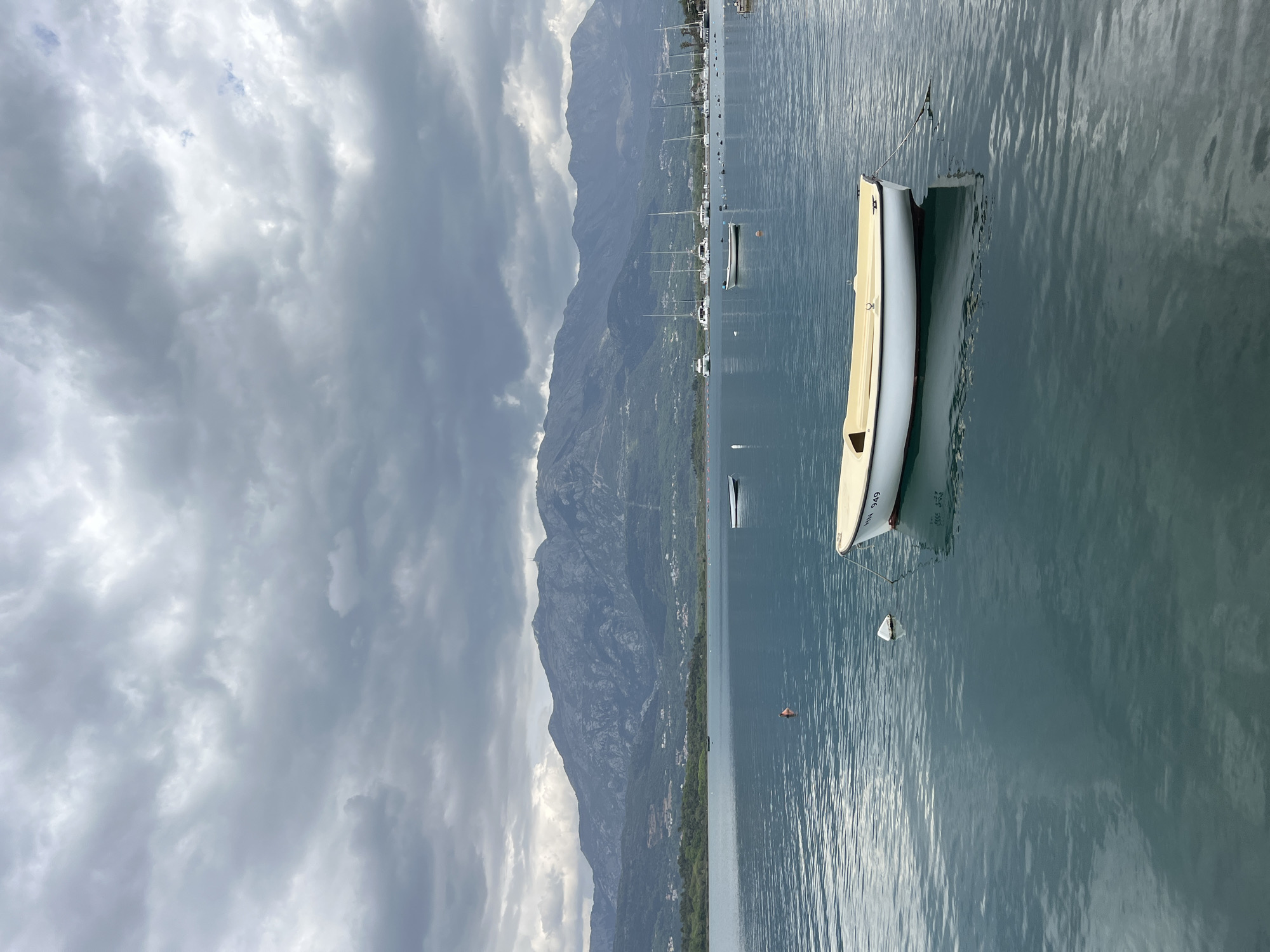 Lone sailor navigates Bay of Kotor under overcast skies