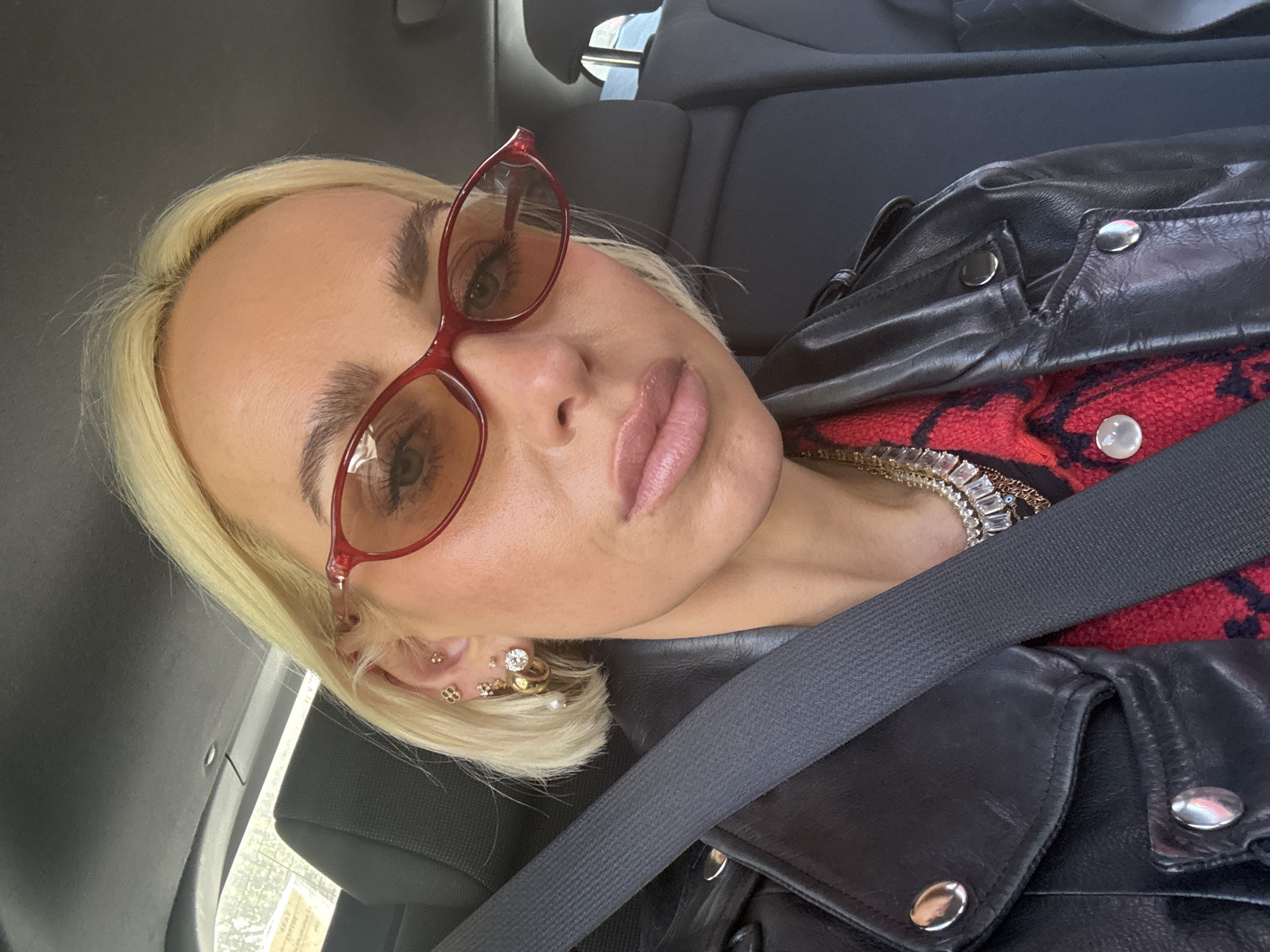 Woman in red sunglasses, leather jacket observed in Milan car