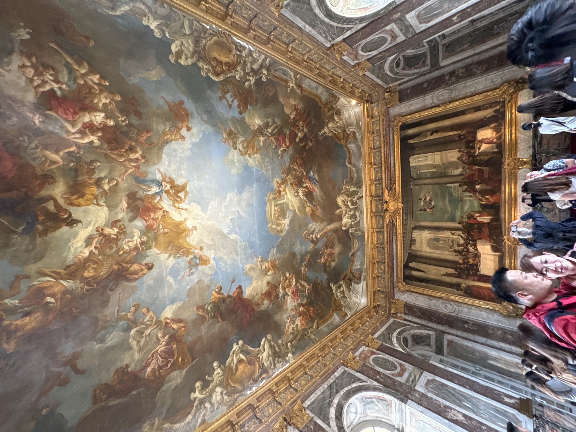 Tourist documents ornate ceiling art at Palace of Versailles