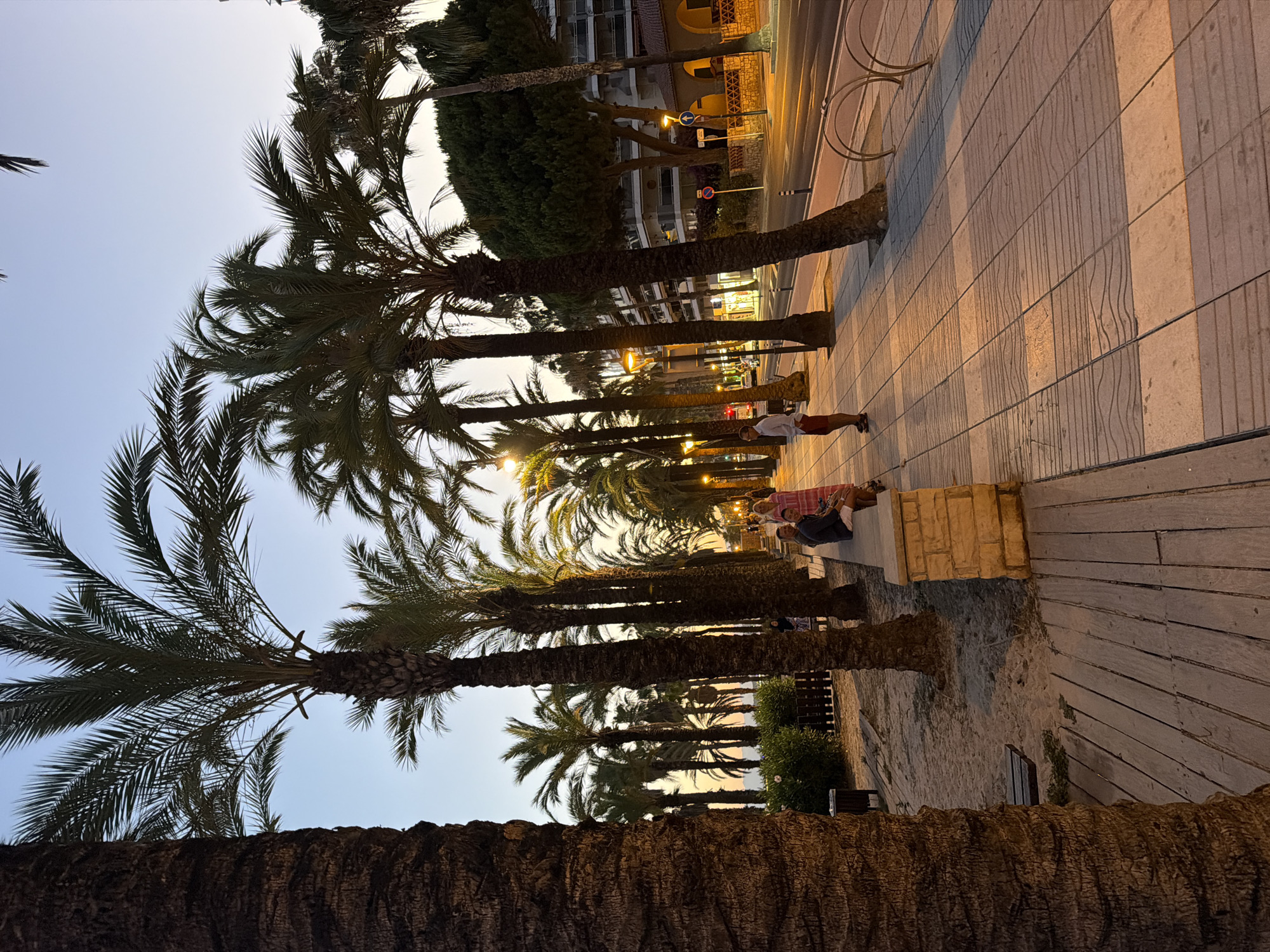 Salou waterfront promenade at dusk, green-lit bar in view