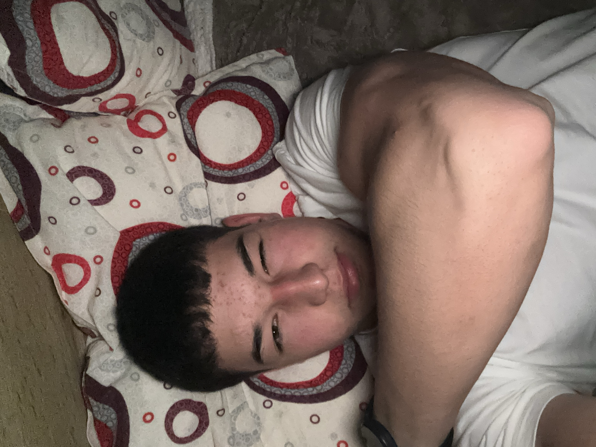 Young man makes playful gestures while lying in bed