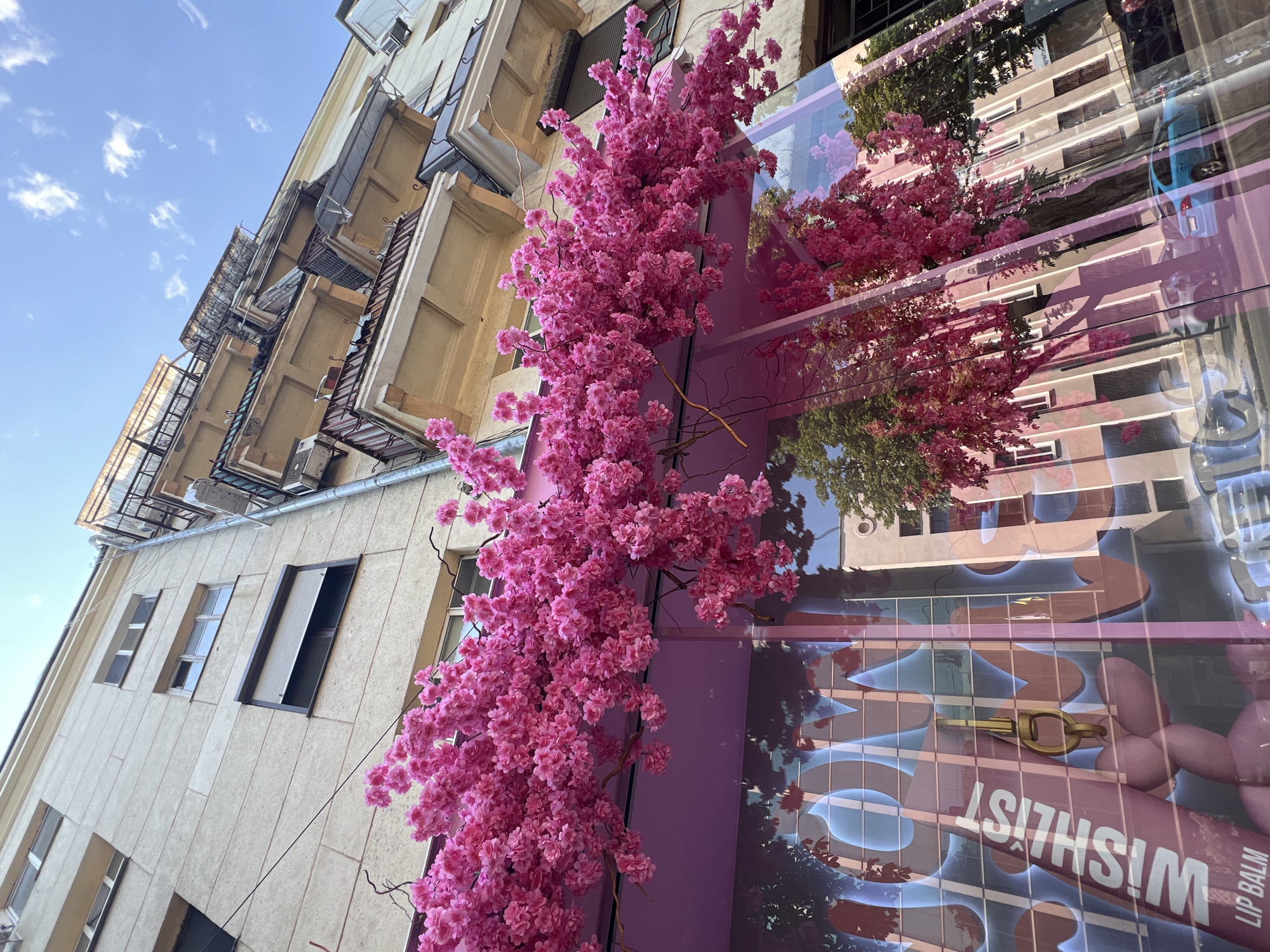 Pink cosmetics storefront with cherry blossoms, Odesa summer street