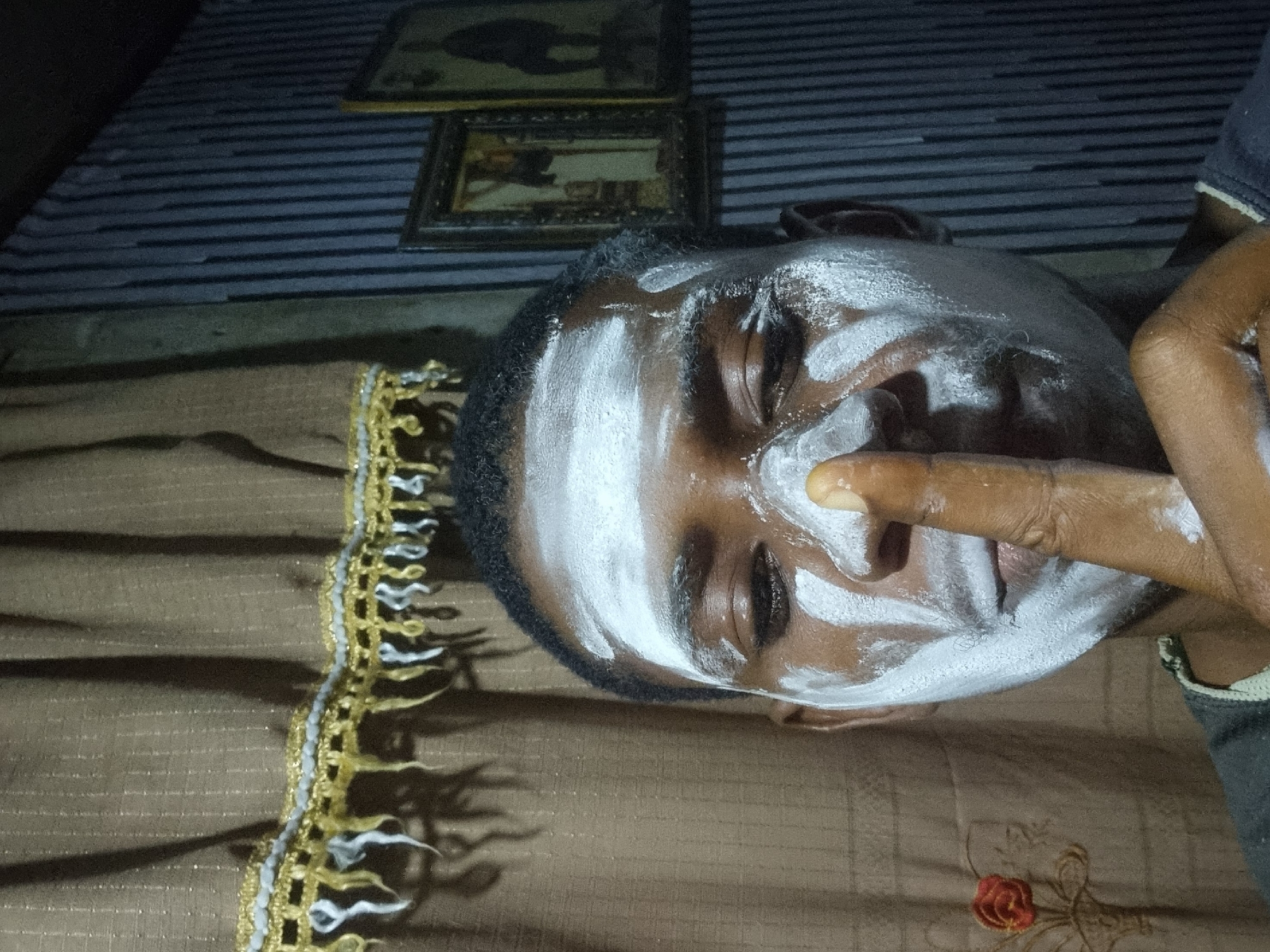 Man applies white face paint in Onitsha home setting