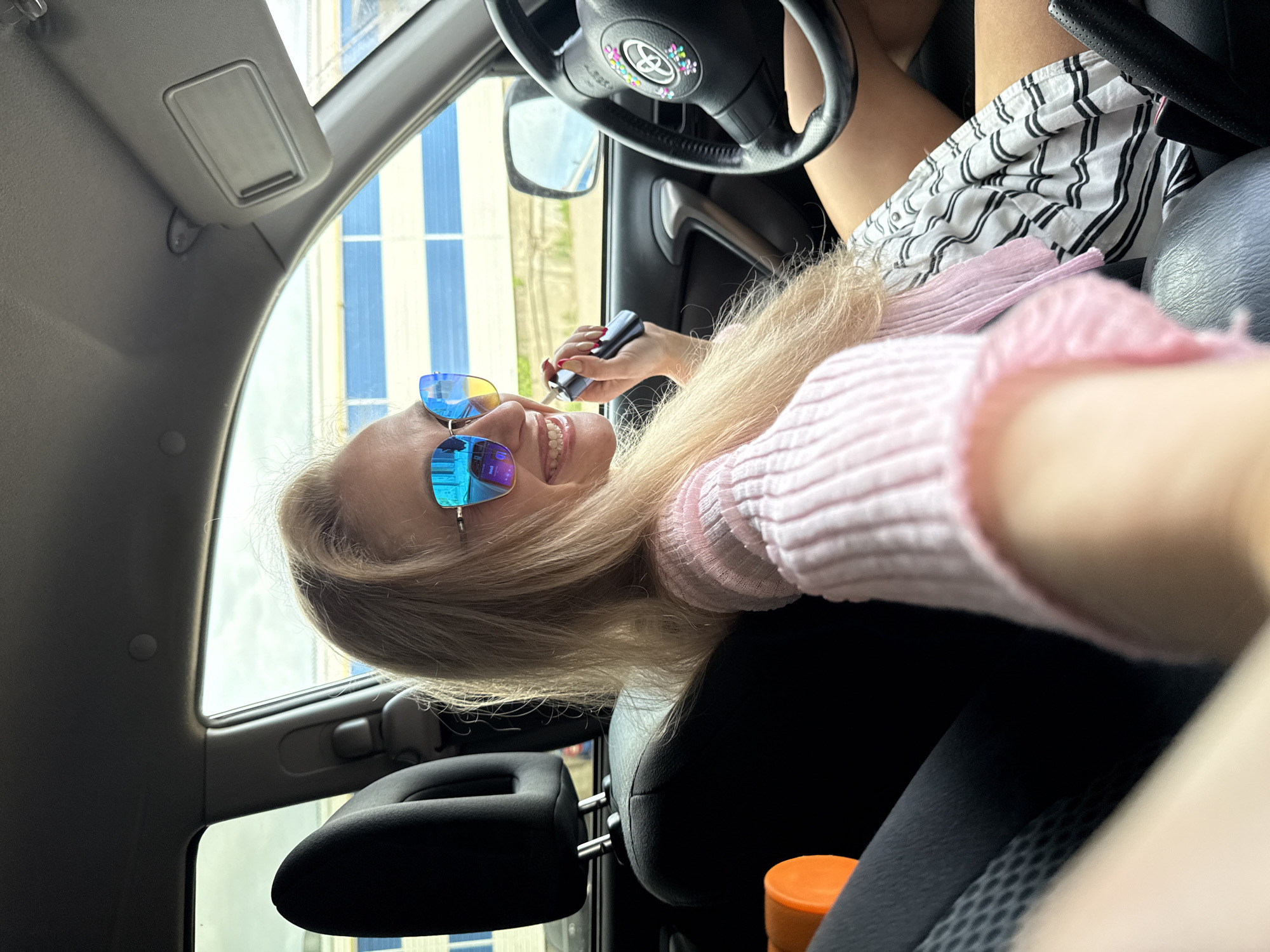 Woman in pink sweater sits in car in Chaikovsky