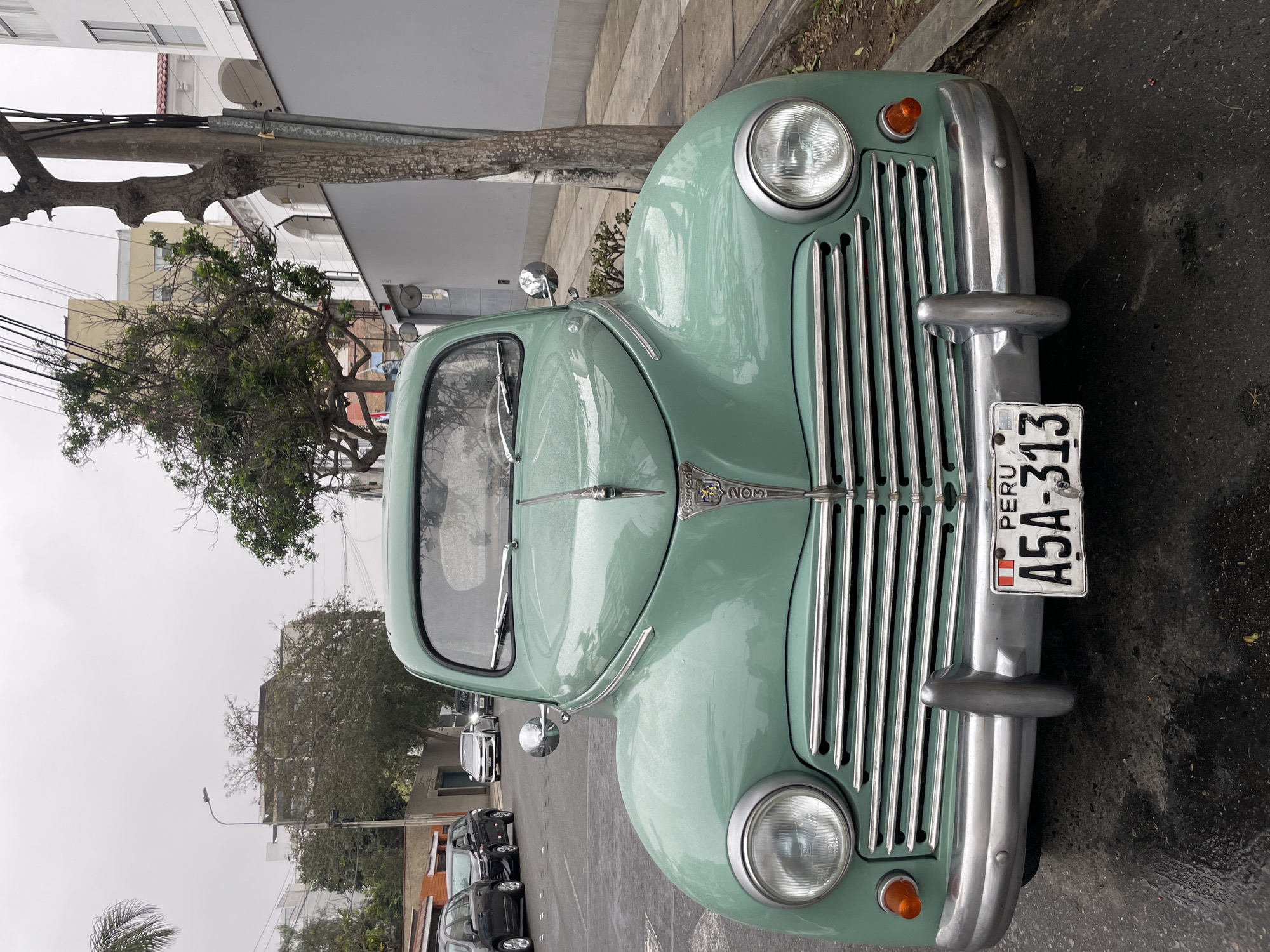 Vintage Peugeot parked on rainy Miraflores street