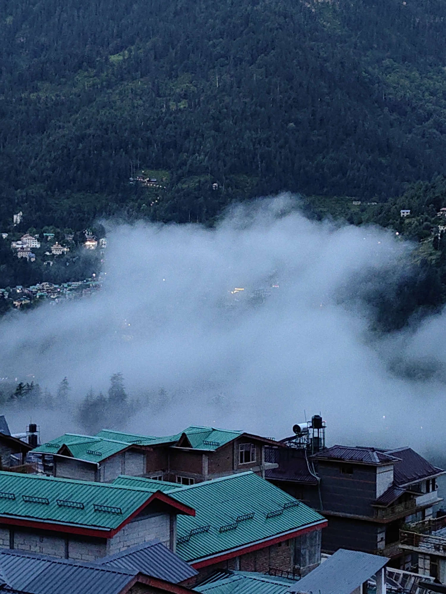 Vashisht at dusk: village, valley, and Himalayan peaks under heavy cloud