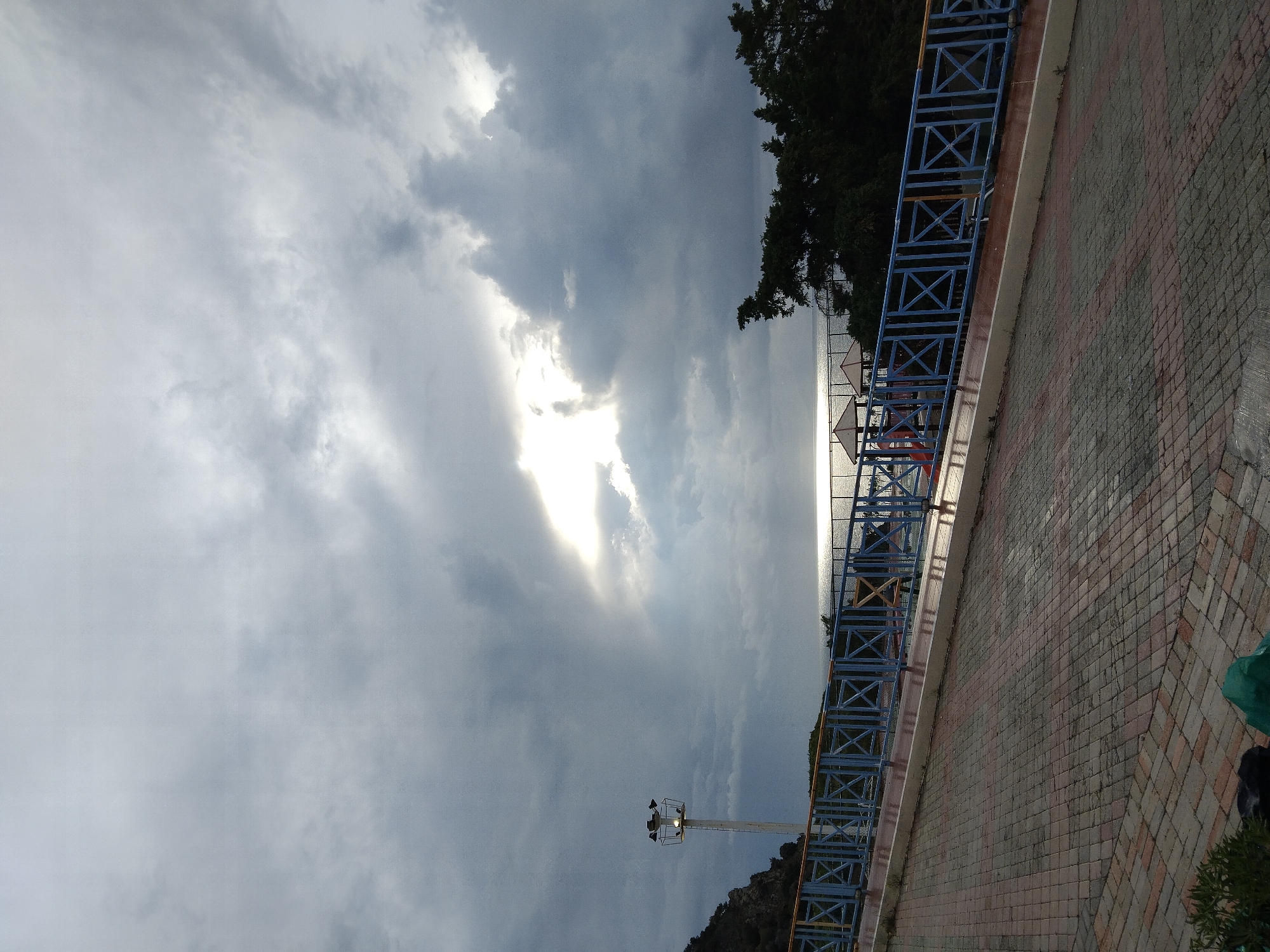 Morning sunlight breaks through clouds over walkway in Zia, Greece