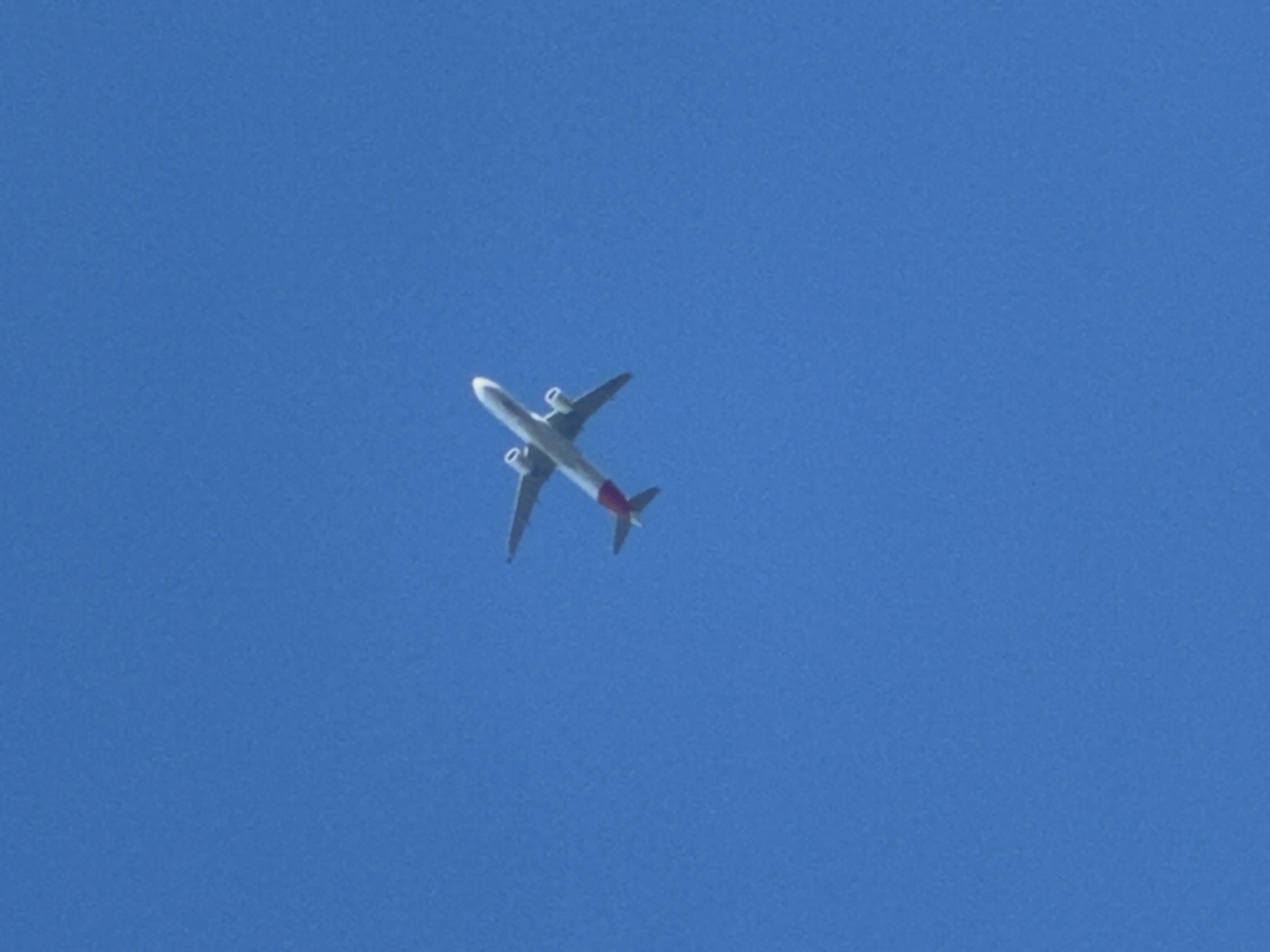 Red-tailed passenger jet crosses clear skies over southeast London