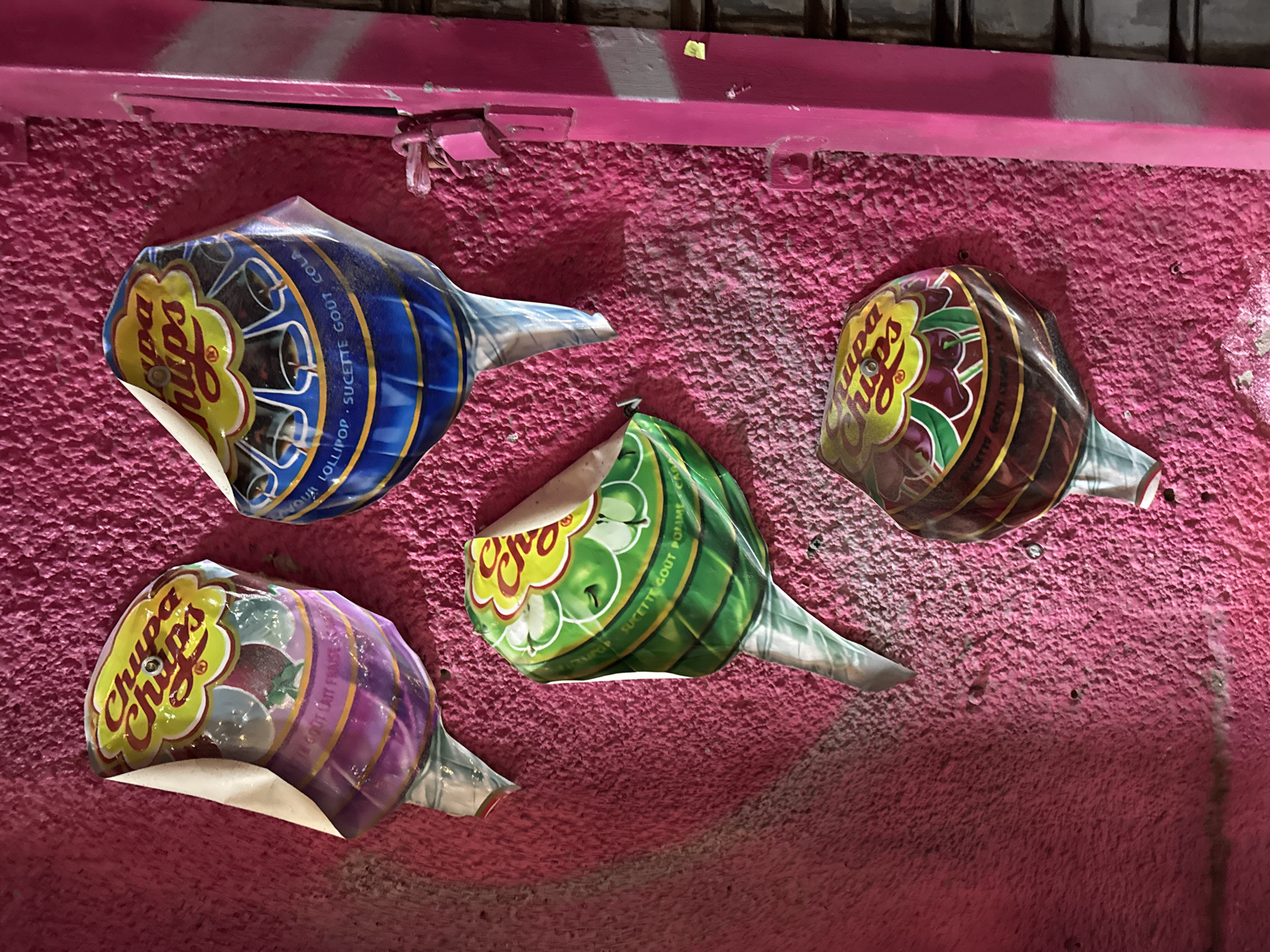 Colorful Chupa Chups wrappers stuck on pink wall