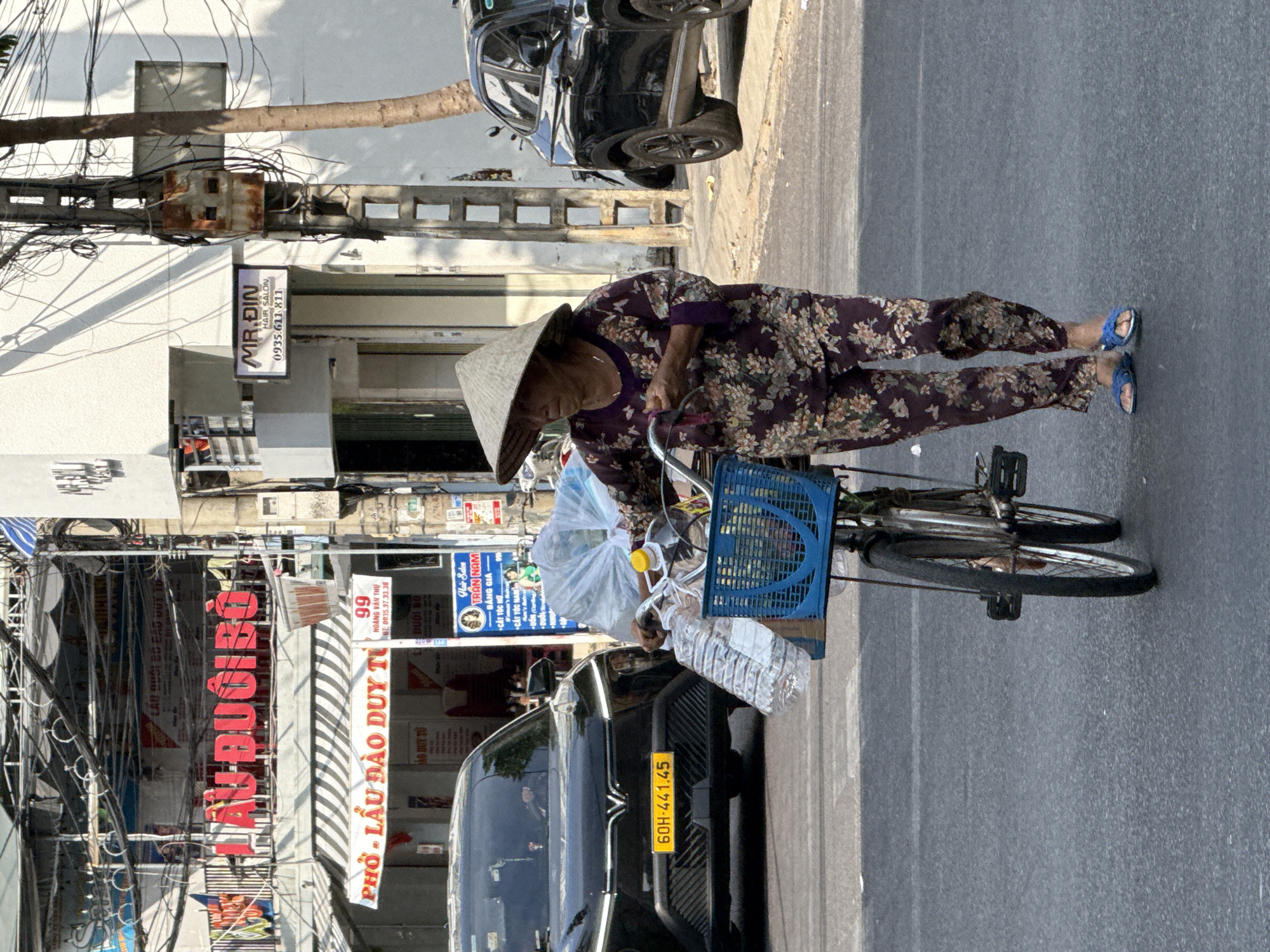 Elderly woman with bicycle, yellow car observed on Nha Trang street