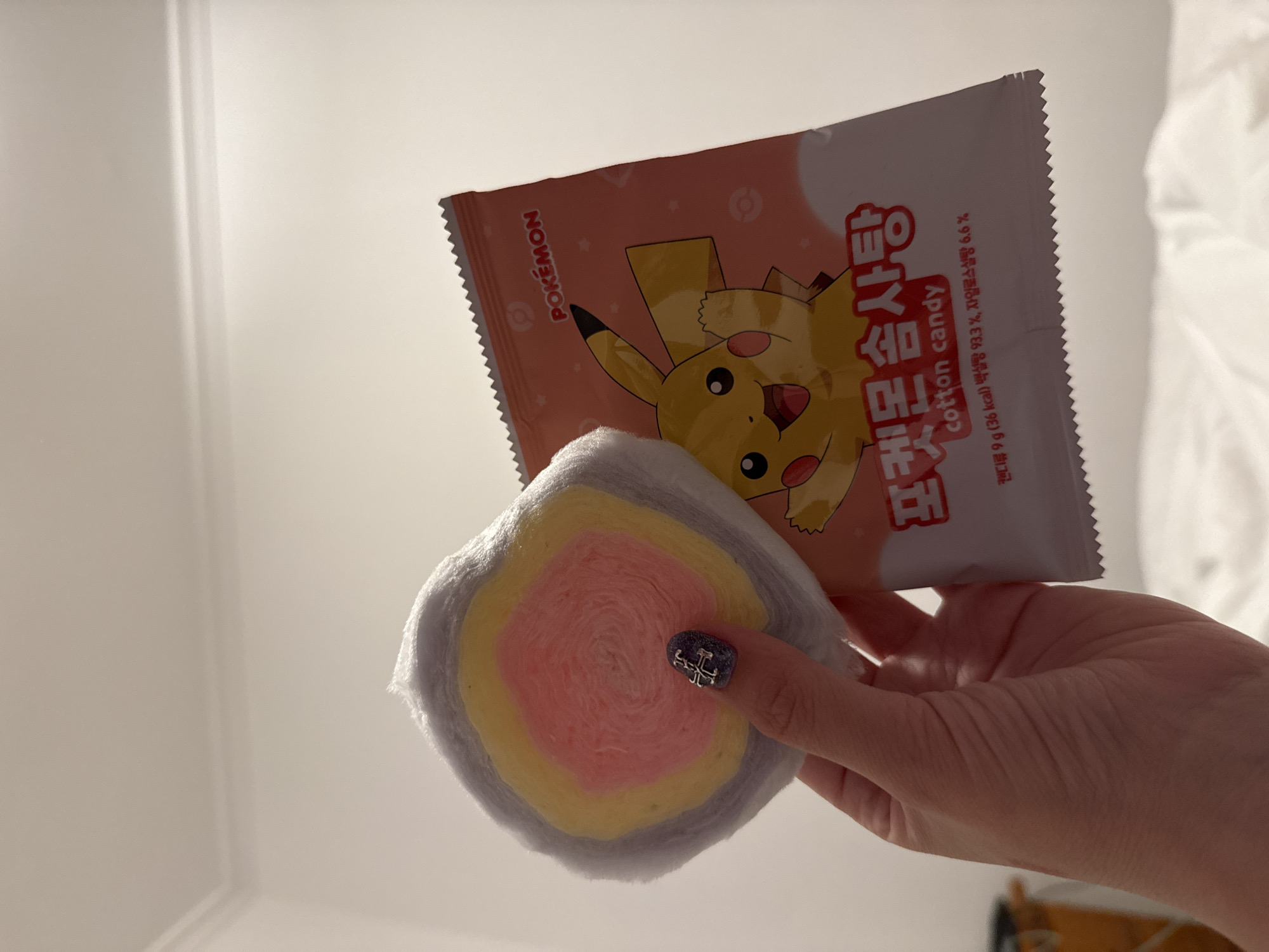 Person holds colorful Pokémon cotton candy at location