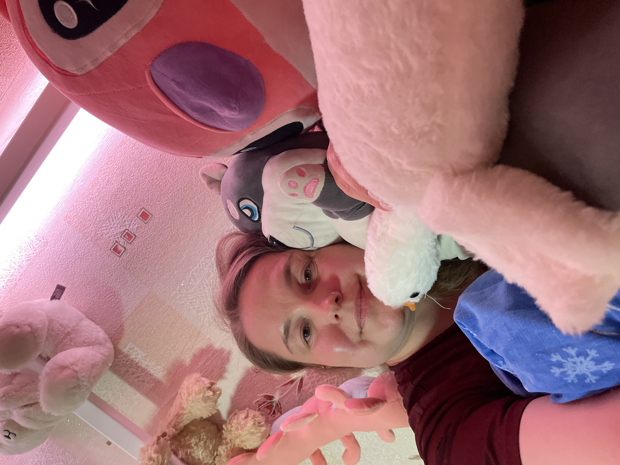 Woman poses with stuffed animal collection in Izhevsk bedroom