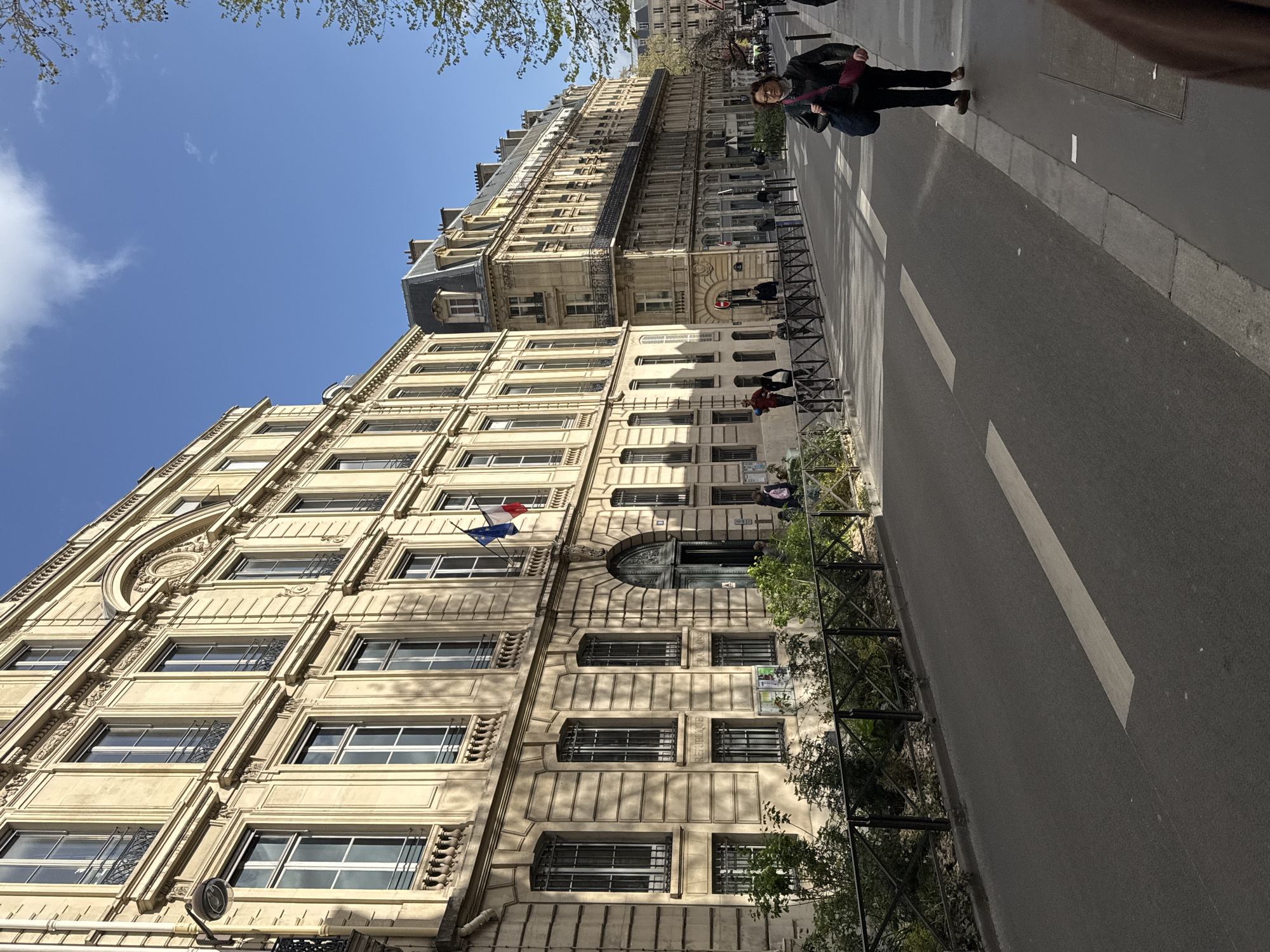 Parisian street displays classical architecture with French flags