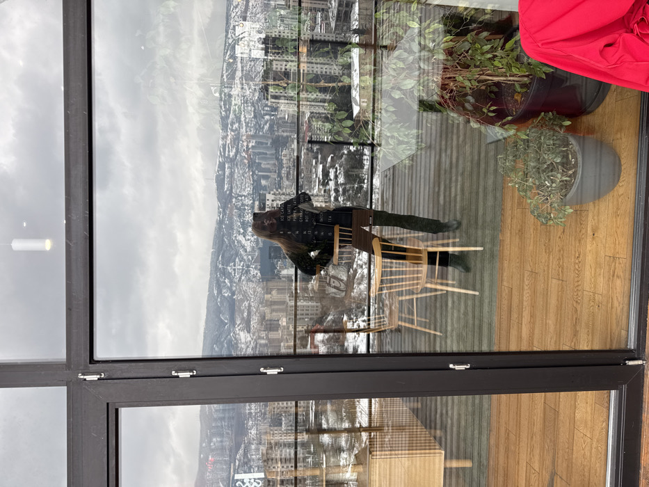 Woman photographs herself on Tbilisi balcony overlooking cityscape